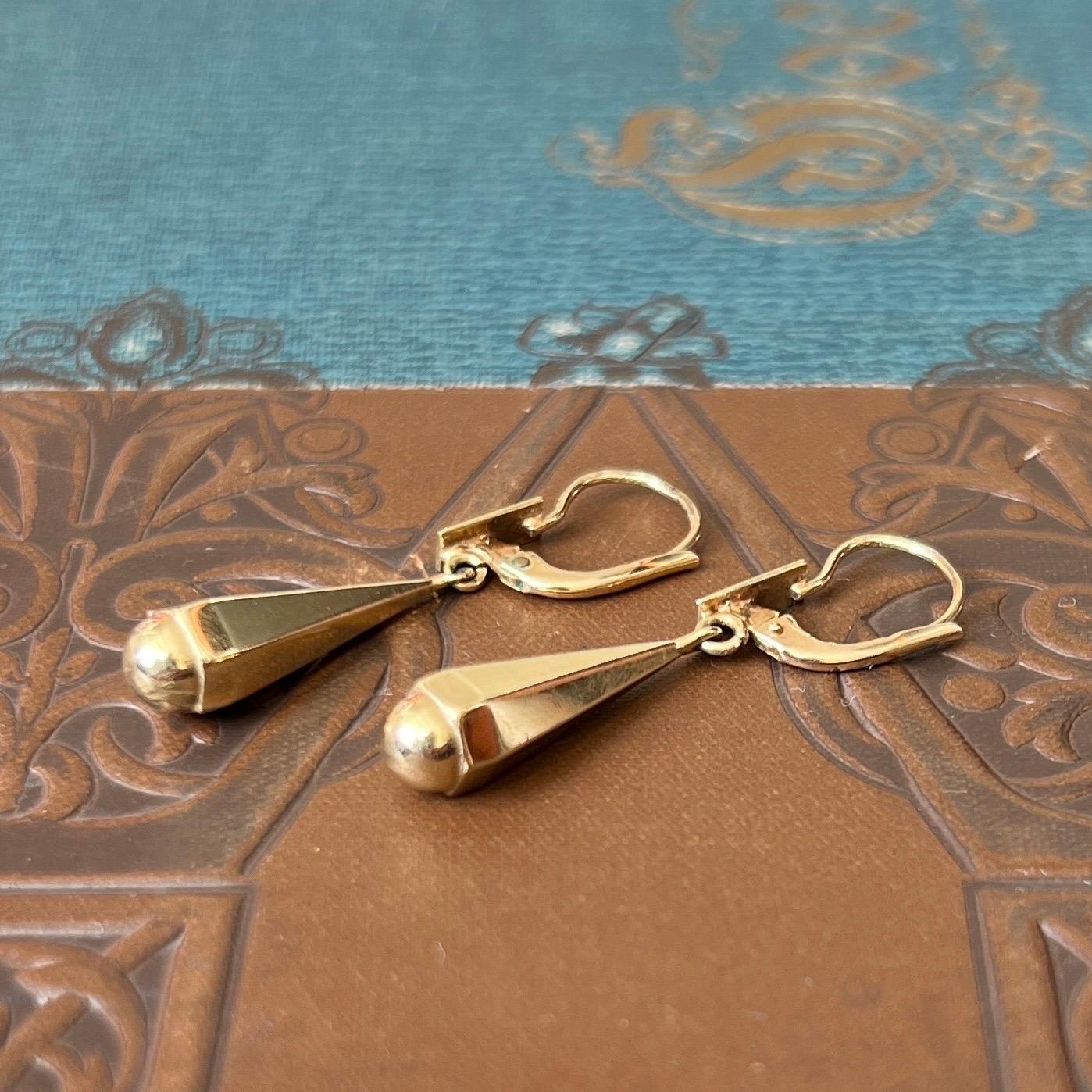 These beautiful vintage 14 karat yellow gold dangle earrings are designed in a tapered hexagon shape. The pendants are hollow cast and are formed in a hexagon and taper towards the top. The ear hooks have a small rectangular-shape applique and the