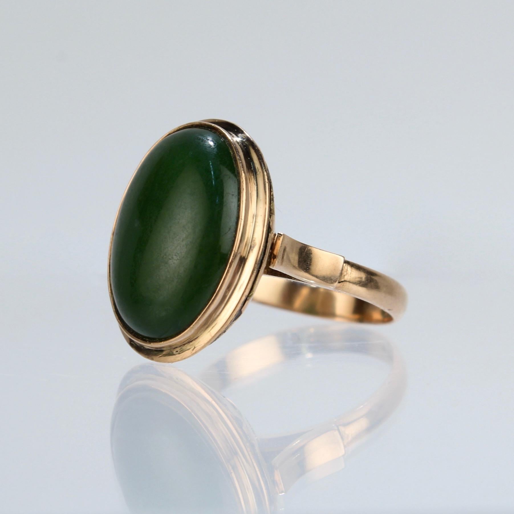 A fine gold and jade cabochon ring in the Chinese taste.

The nephrite jade cabochon is dark green in color and is bezel set in a setting with a pierced gallery on the underside. This openwork allows light to enter the stone from the underside.