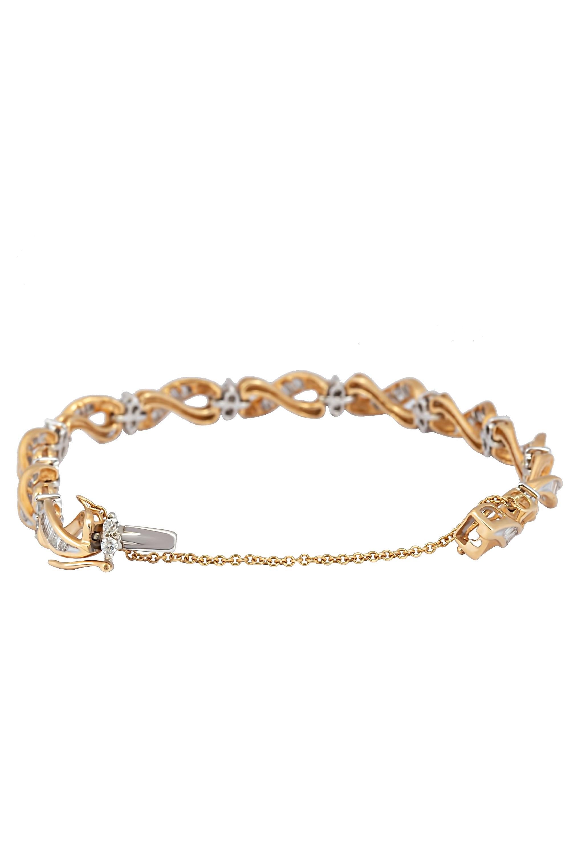 This graceful and sinuous bracelet is composed of brightly polished yellow gold infinity links set with gleaming white gold centers of bright baguette diamonds punctuated by white gold stations of two round brilliant diamonds. Crafted in 14 karat