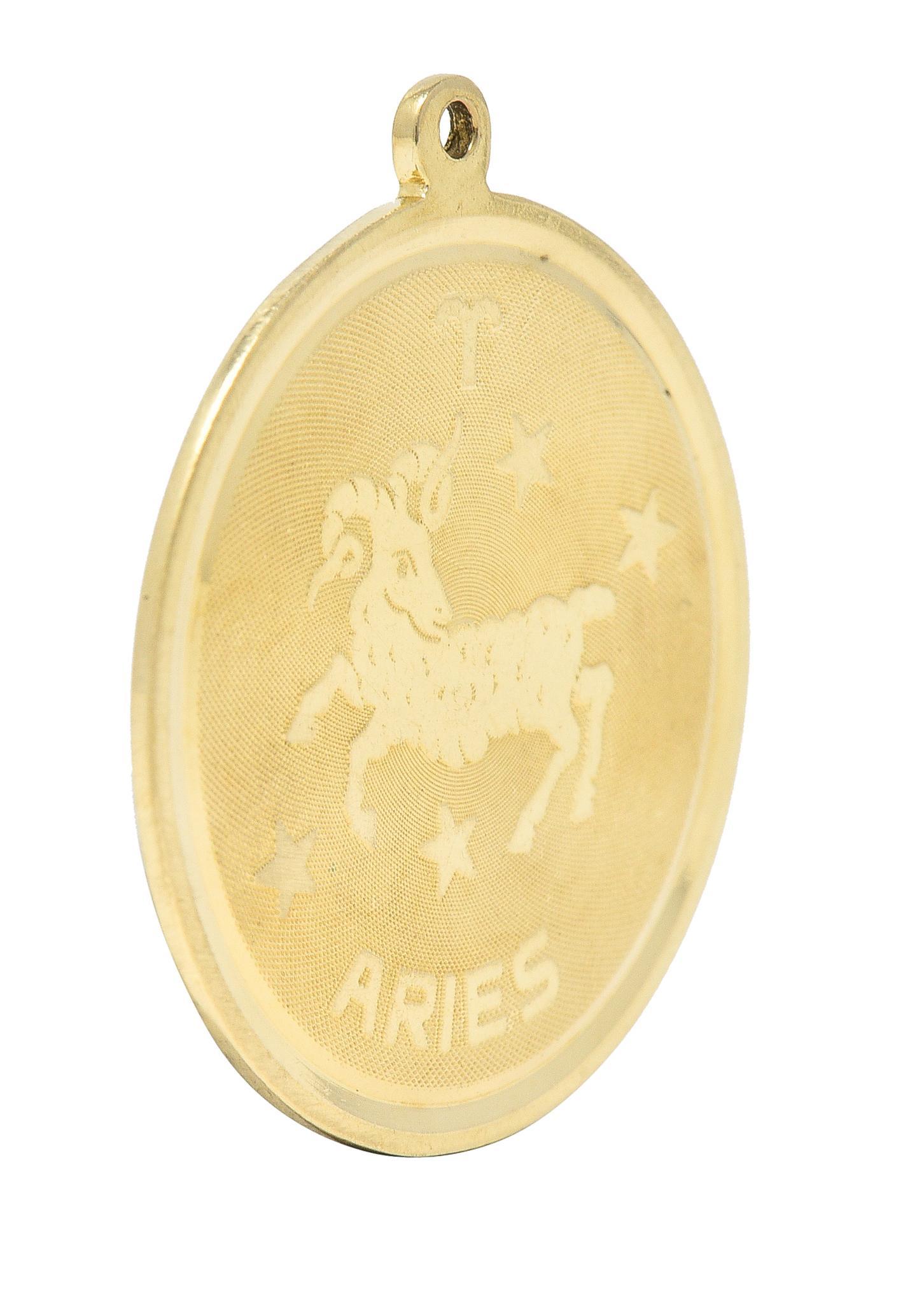 Designed as a round disk with high polished edges and a raised Aries zodiac motif
With the astrological Aries symbol, a ram, stars, and inscribed 'Aries'
With a finely cross-hatch textured recess
Completed by pierced bale
Tested as 14 karat