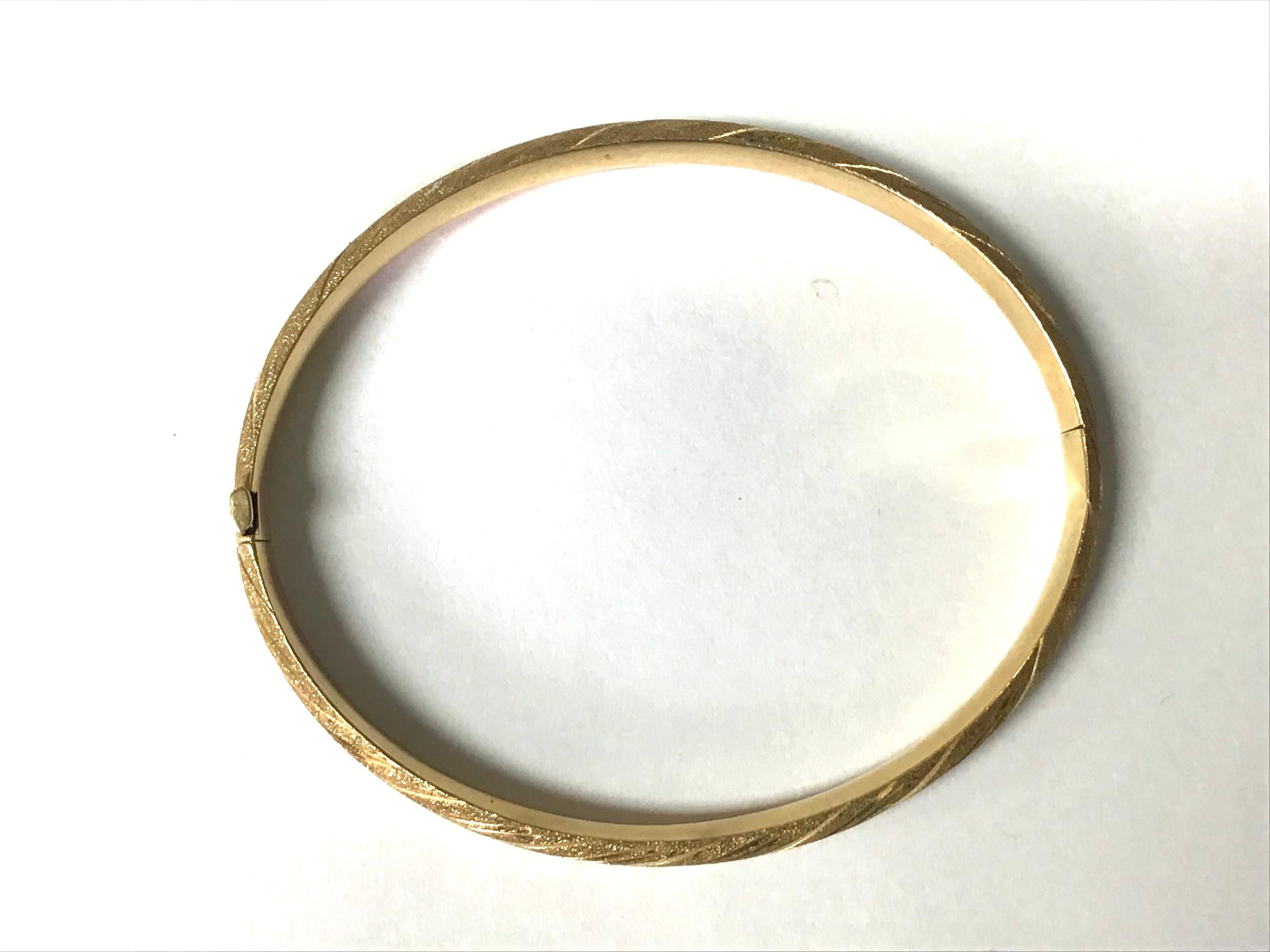This timeless bangle bracelet is made of 14 karat yellow gold. It has a wonderful warm glow and a weight of 6.9 grams. The bracelet has a nice height of 7 millimeters, is oval shaped and hinged. The bracelet is marked at its closure 14K. This lovely