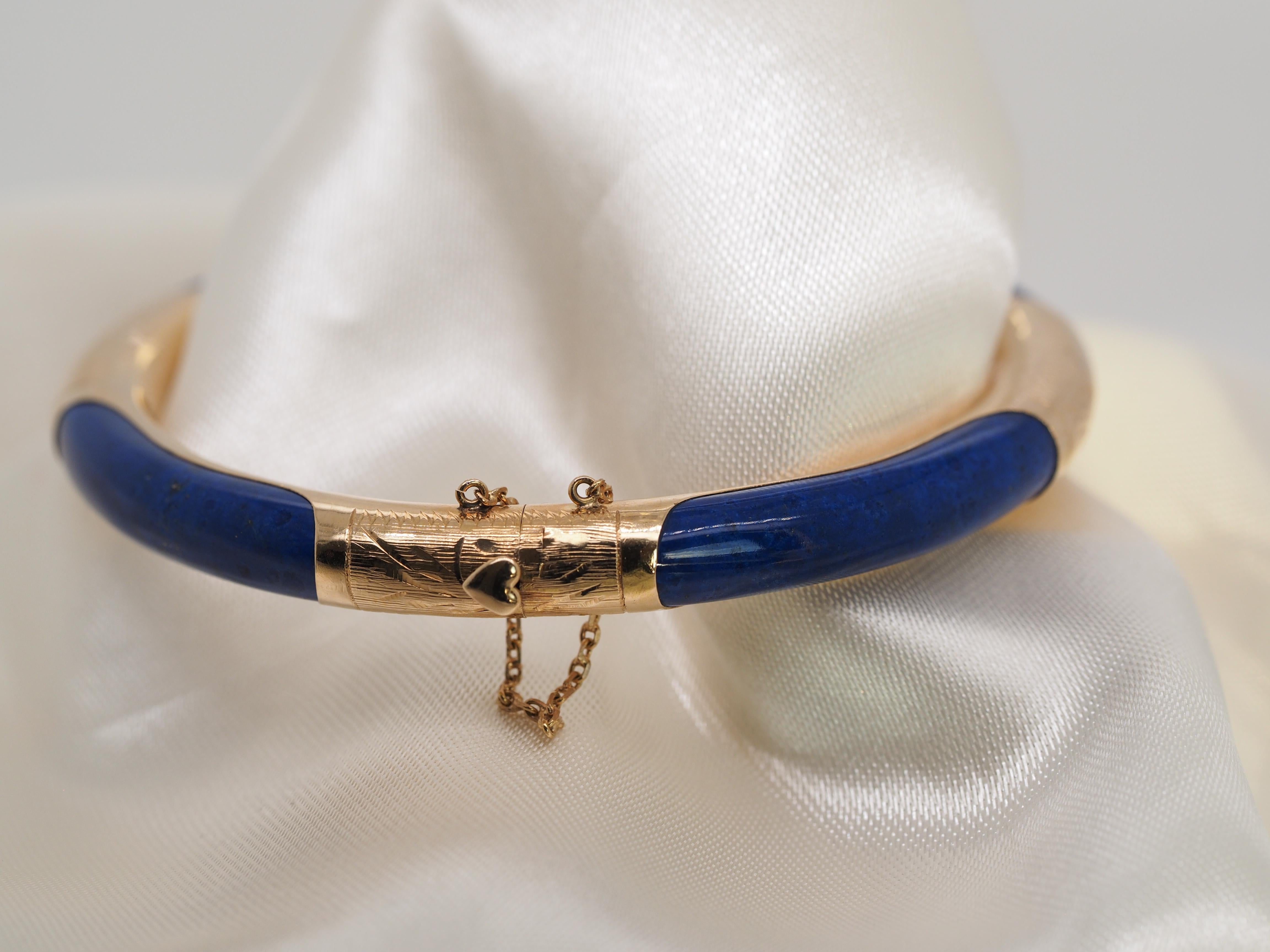 Vintage 14 karat Yellow Gold hinged Lapis Bangle bracelet with a dangle chain on the clasp. The clasp has a detail of heart that pushes down to open the bracelet. It is in excellent condition  perfect for any occasion. 

Item Details:
Metal Type: