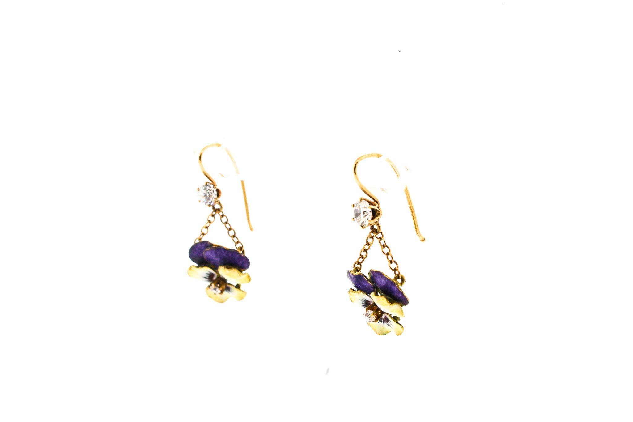A pretty vintage pair of yellow and purple enamel 18k yellow gold pansy flowers made into a hanging earring. The flower itself dates to about 1950 and were likely stick pins originally. The pair currently hang from chain and are suspended from two