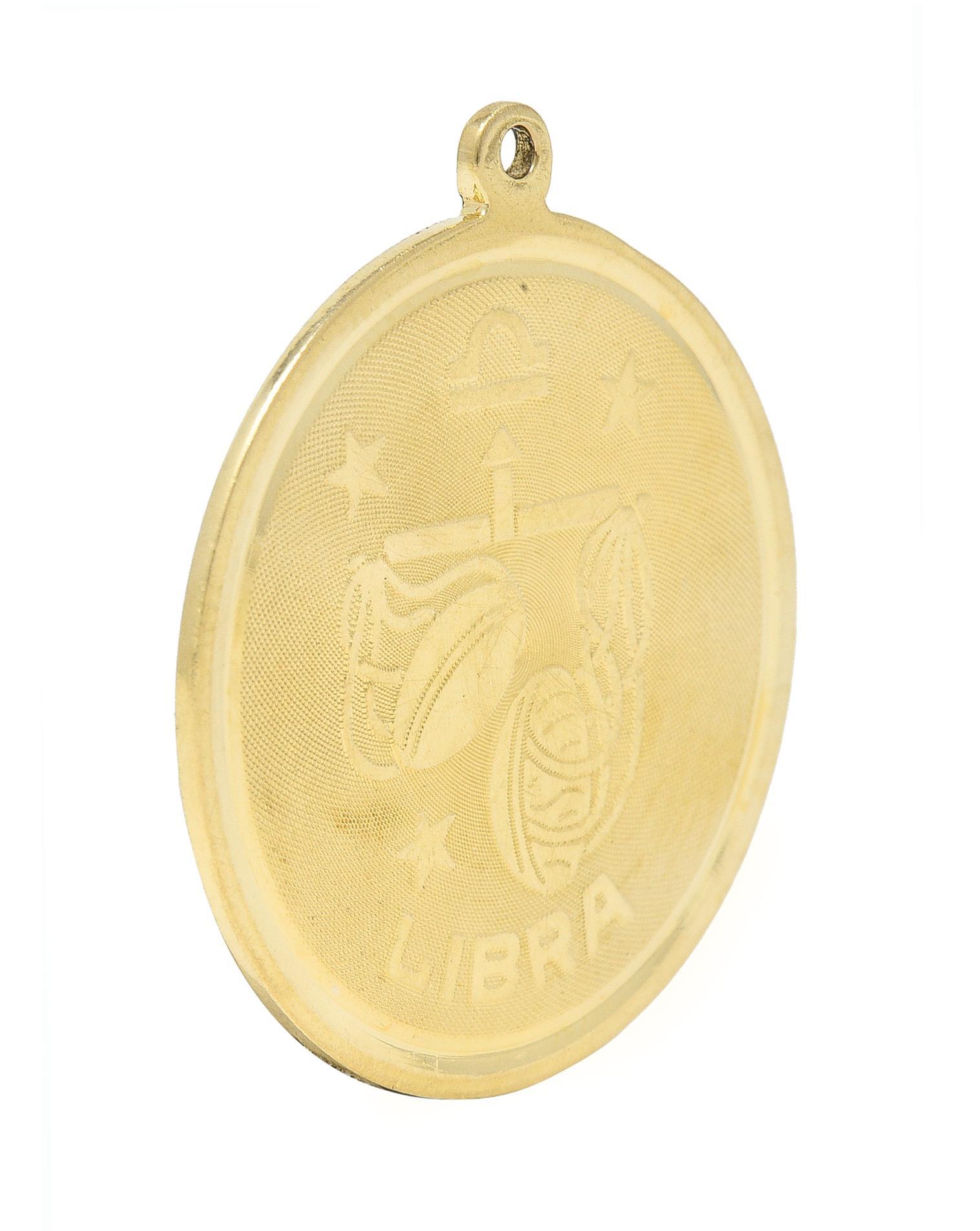 Designed as a round disk with high polished edges and a raised Libra zodiac motif
With the astrological Libra symbol, stylized scales, stars, and inscribed 'LIBRA'
With a finely cross-hatch textured recess
Completed by pierced bale
Tested as 14