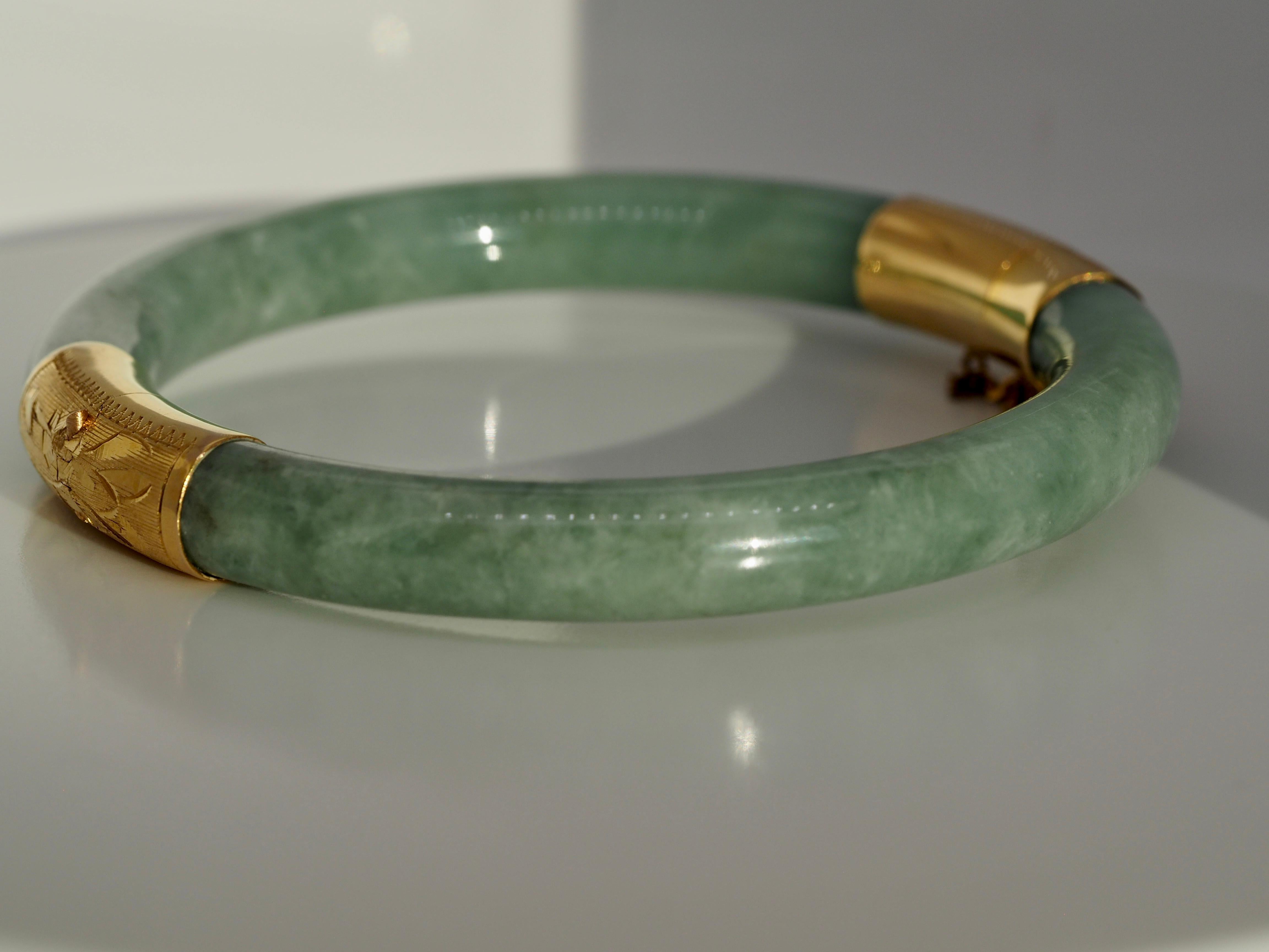 Vintage 14 karat yellow gold light jade bangle bracelet. This beautiful bangle bracelet has a tongue and groove clasp with safety chain connecting both ends of the bracelet. It is in excellent condition perfect for everyday wear or for any occasion.