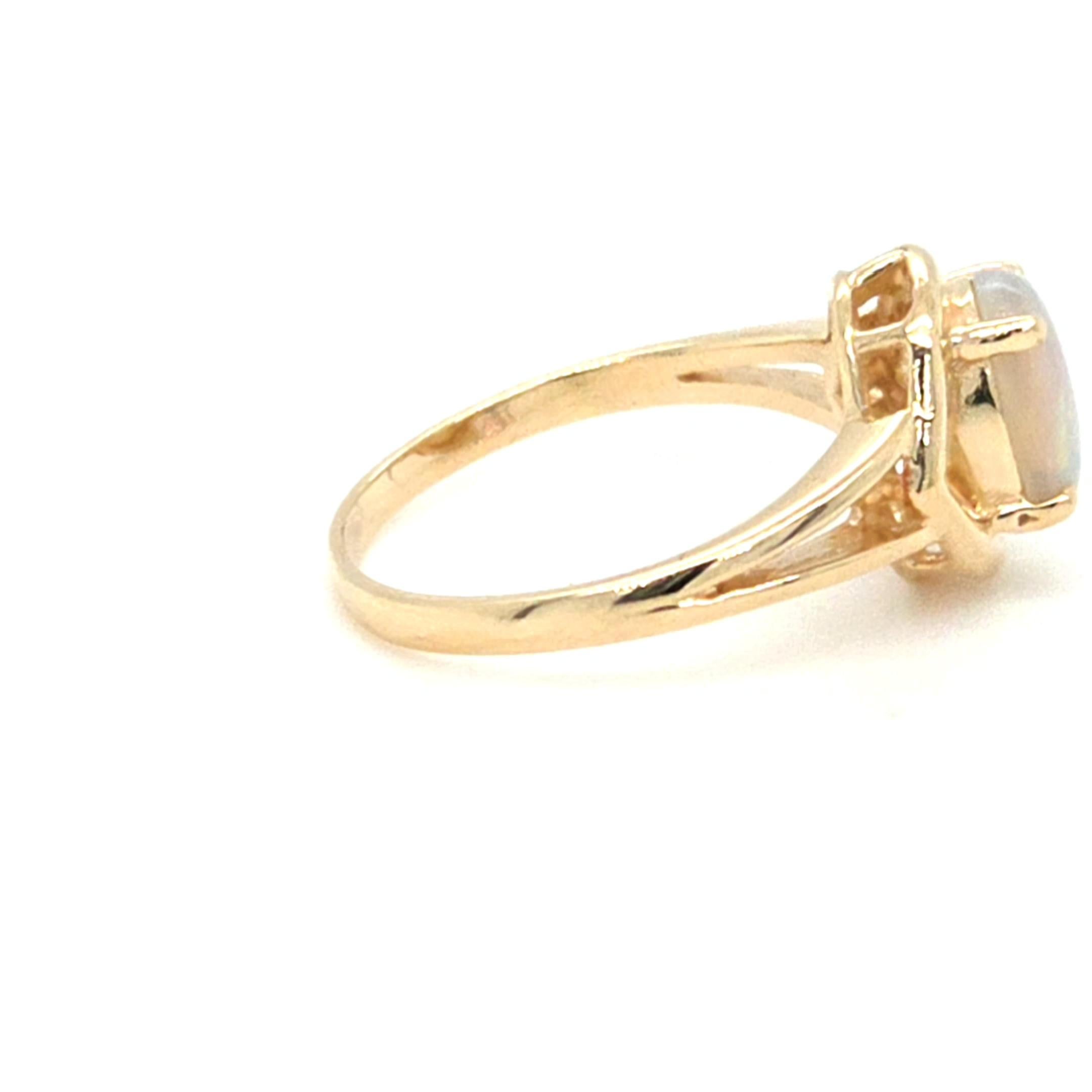Cette bague vintage en or jaune 14 carats est une vitrine gracieuse de la beauté naturelle et de l'artisanat intemporel. En son centre se trouve une opale ovale lumineuse mesurant environ 8 mm x 6 mm, sertie en chaton pour mettre en valeur le jeu de