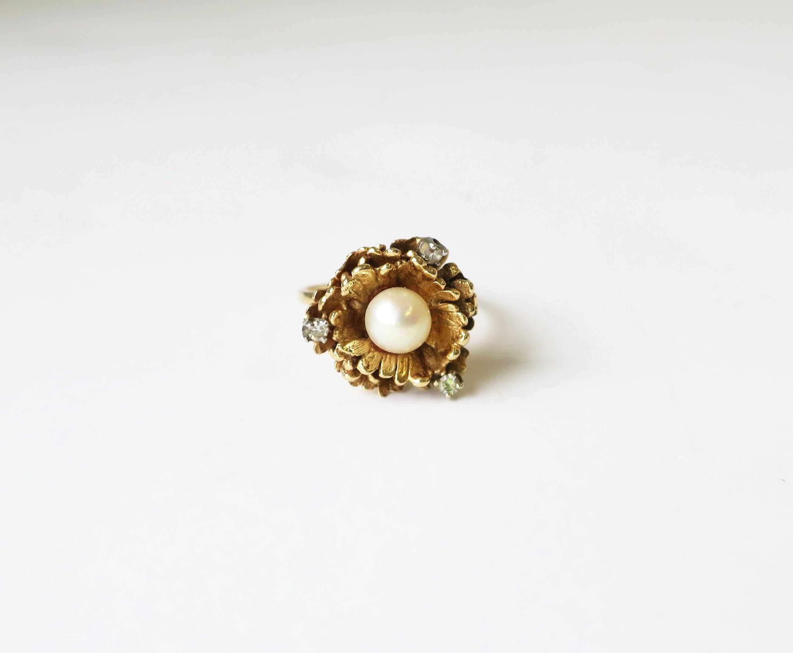 A vintage 14-karat yellow gold, cultured pearl, and diamond cocktail ring, circa mid-20th century, 1960s. Ring has a 14-karat yellow gold flower form, a center cultured pearl, and three (3) diamonds - all prong set in 14-kt white gold. Ring is a