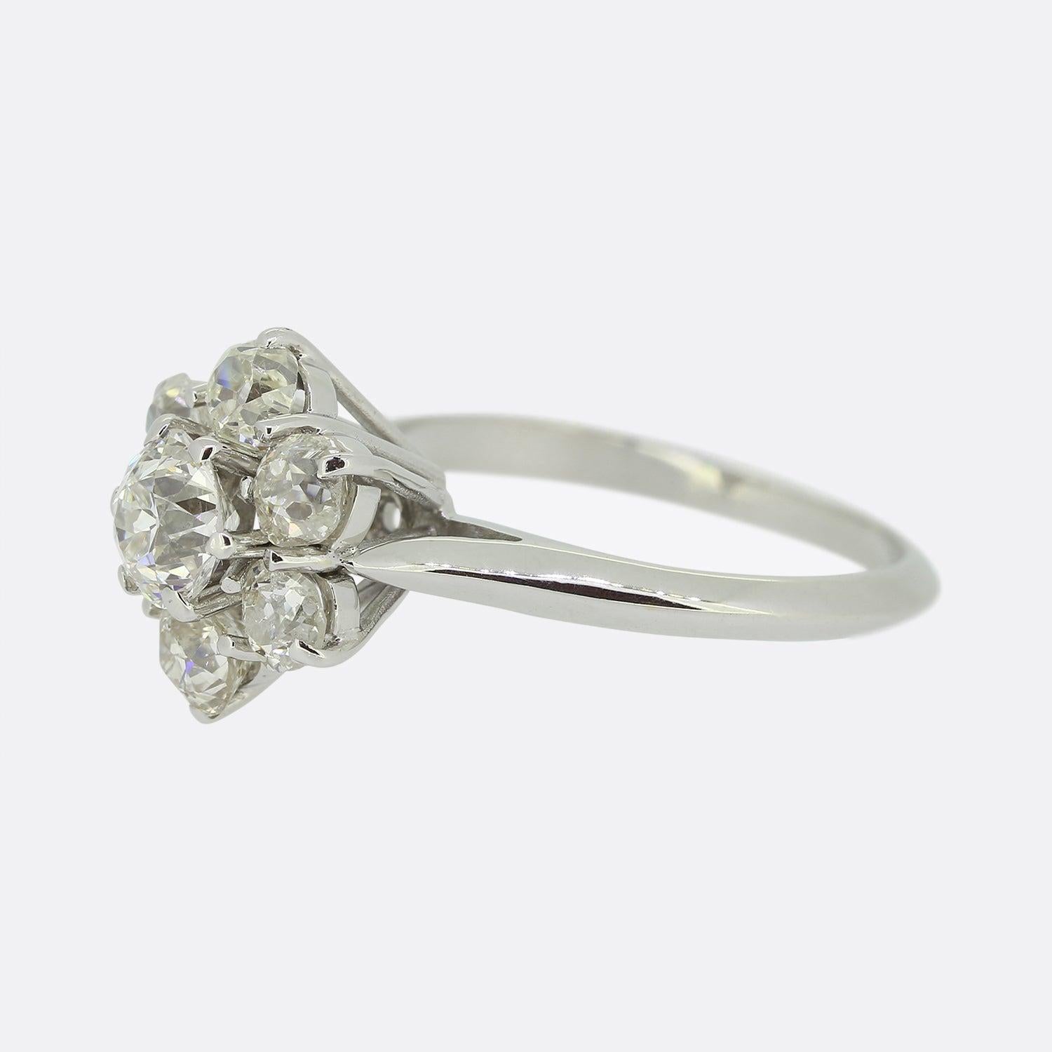 Here we have an absolutely shimmering diamond cluster ring. A bright white 0.60ct round faceted old cut diamond sits slightly risen at the centre of the face. This principle stone is surrounded by an array of slightly smaller matching stones around