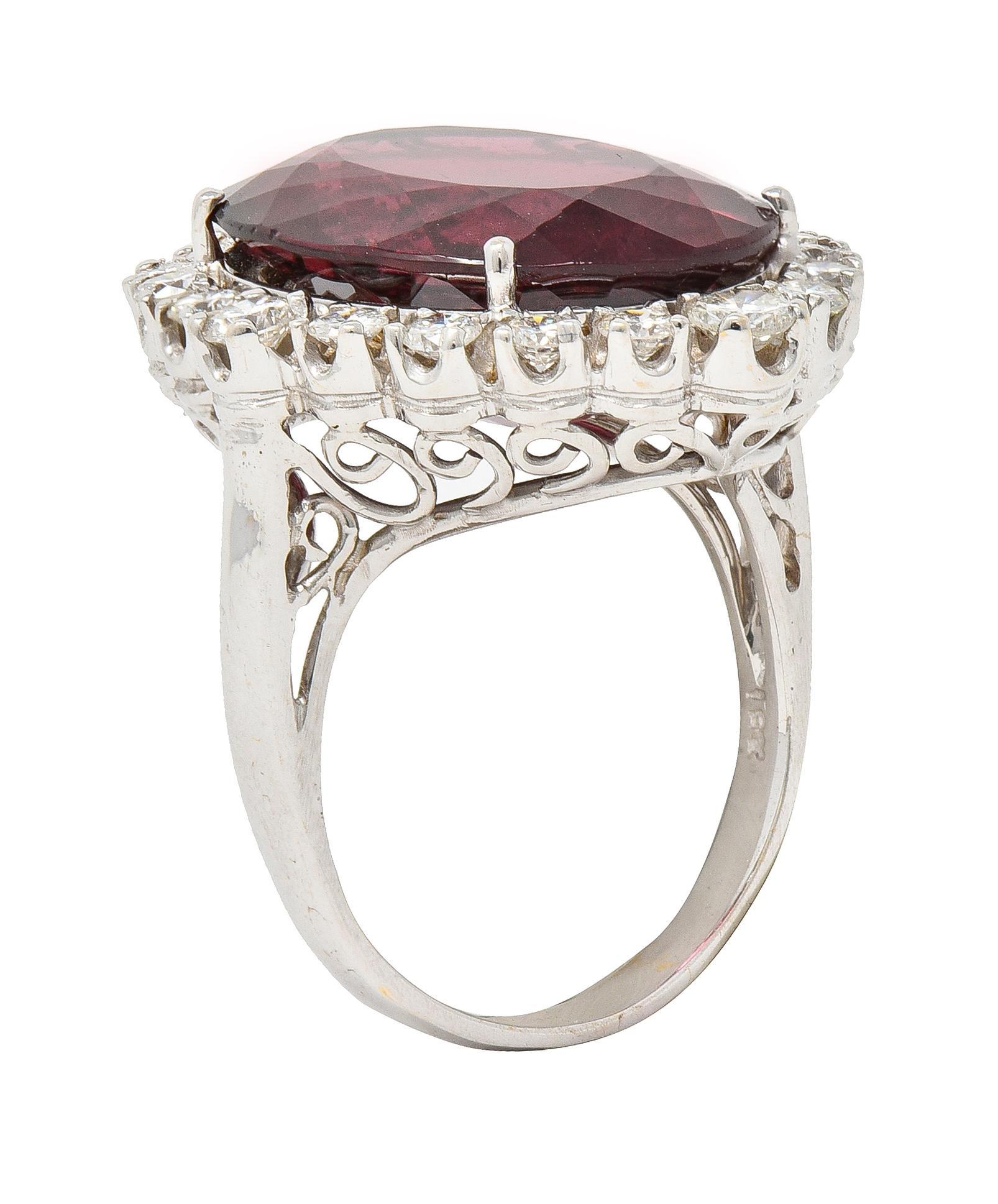 Cluster ring features an oval mixed cut rubellite tourmaline weighing approximately 13.65 carats
Medium dark red in color and surrounded by a round brilliant cut diamond halo
Weighing in total approximately 1.25 carats with H/I color and VS