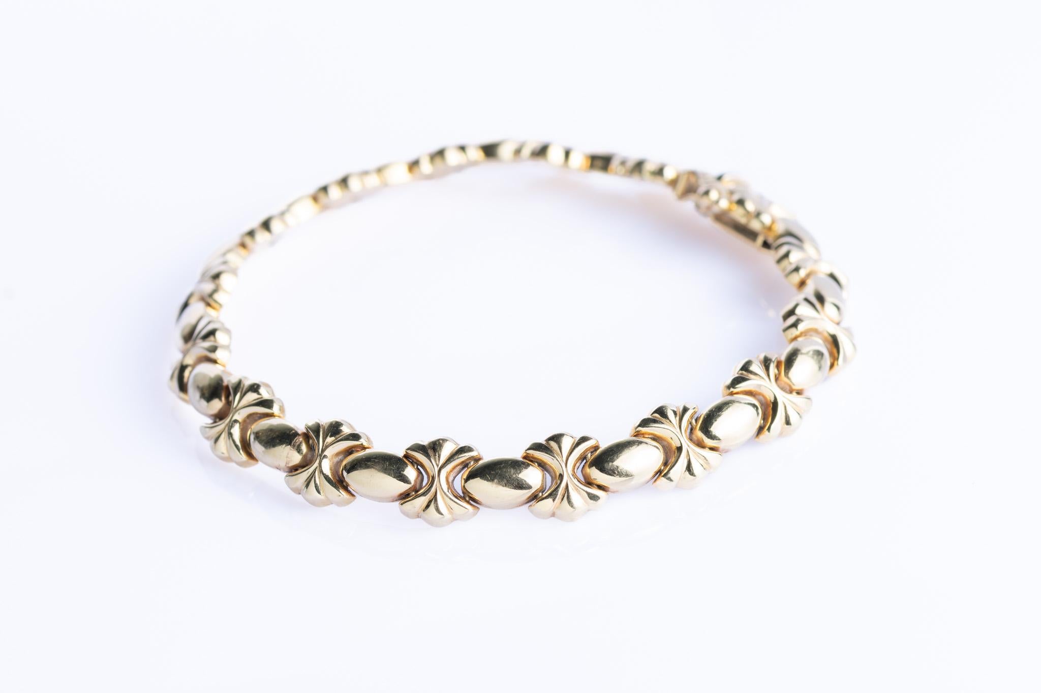 A striking vintage bracelet in 14ct gold designed with a continuous pattern of bow-shaped links. Each link is sculptural and decorative, catching the light with a warm, polished glow. The repeating motif gives the piece a sense of rhythm and