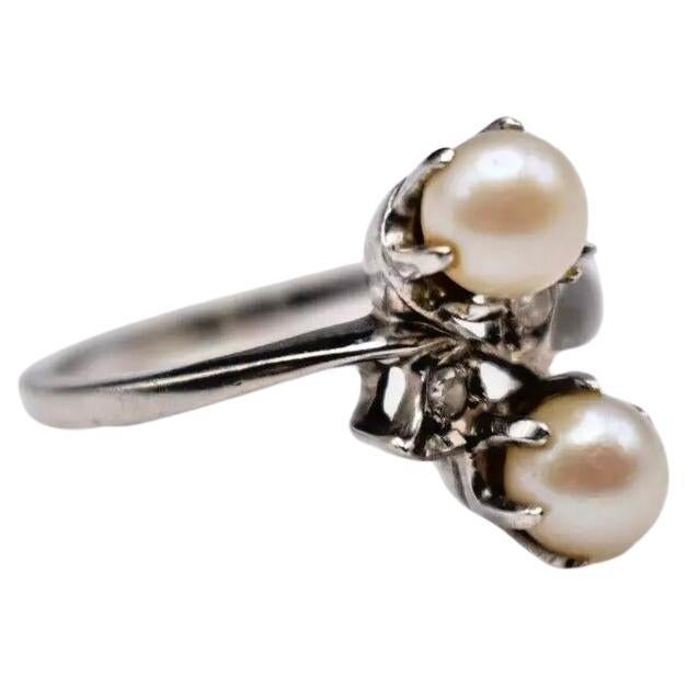 Dieser elegante ausländische Ring aus der zweiten Hälfte des 20. Jahrhunderts ist ein beeindruckendes Beispiel für klassisches Design und raffinierte Handwerkskunst. Der aus 14-karätigem Weißgold gefertigte Crossover-Ring ist mit einem Paar