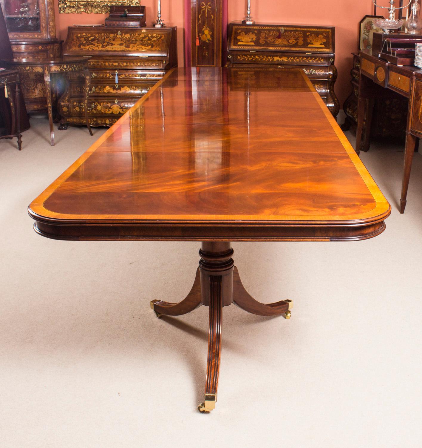 Il s'agit d'une superbe table de salle à manger Vintage de style Regency, fabriquée en acajou flammé, avec un superbe décor de bandes croisées en bois satiné sur le plateau et datant de la seconde moitié du 20ème siècle.

Capable d'accueillir seize