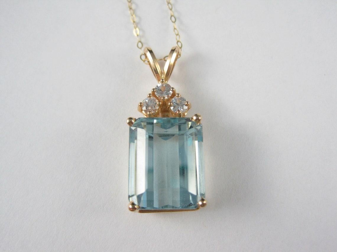 This gorgeous pendant is 14k yellow gold.
It features .30 ctw in natural round diamonds and a stunning 14.8 carat blue topaz.

The diamonds are estimated to be H in color and SI in clarity.

Measurements: 1/2 by 1 3/16 inches.

Marks: 14K, starburst