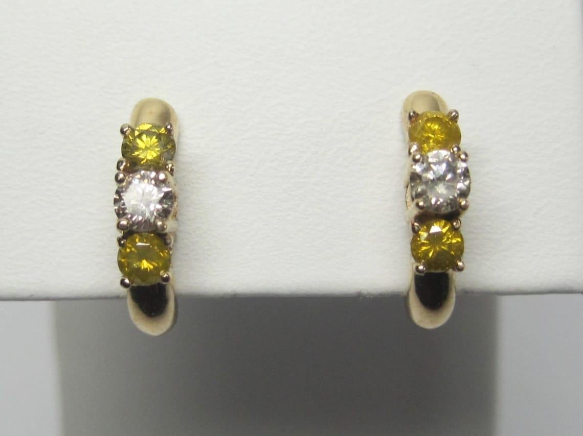 These beautiful diamond earrings are 14k yellow gold.

They feature 2 white diamonds, each measuring .15 carats and 4 fancy yellow diamonds, each measuring .10 carats.

These earrings measure 9/16 of an inch long.
Weight: 1.7 grams

Marks: 14K,