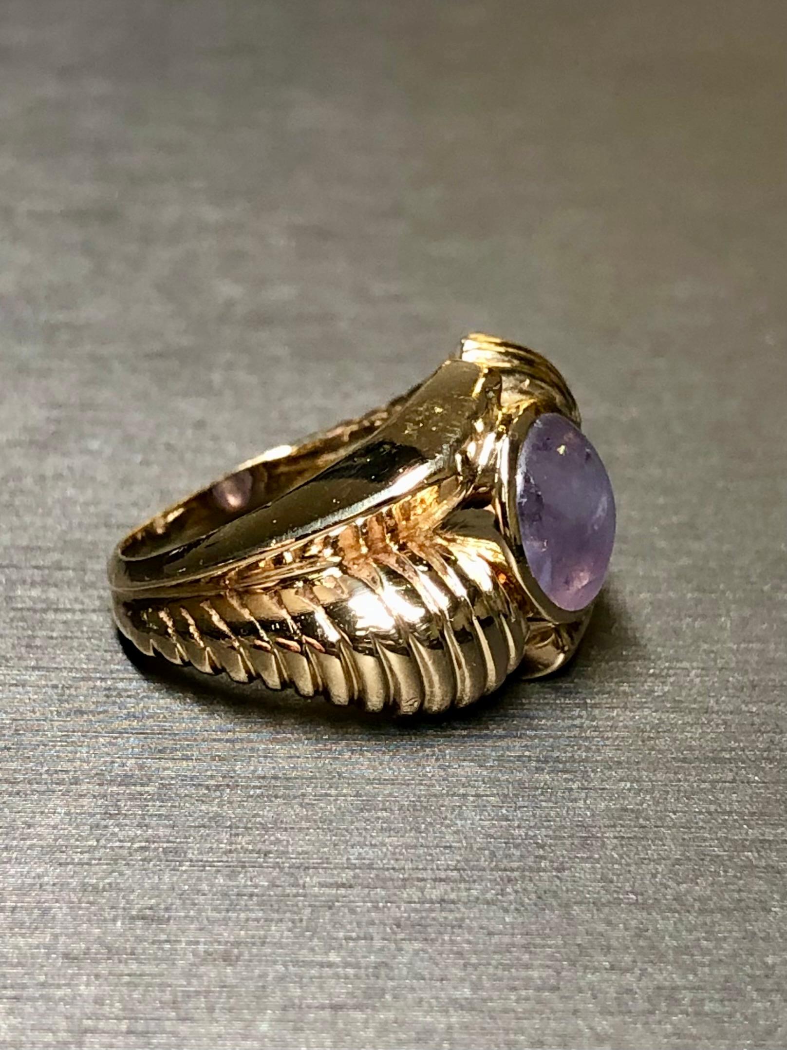 A lovely vintage ring circa the late 1950s done in 14K yellow gold and centered by an approximately 3.50ct natural no heat cabochon star sapphire, exhibiting a very pleasant purple blue color. A very distinctive style reminiscent of the