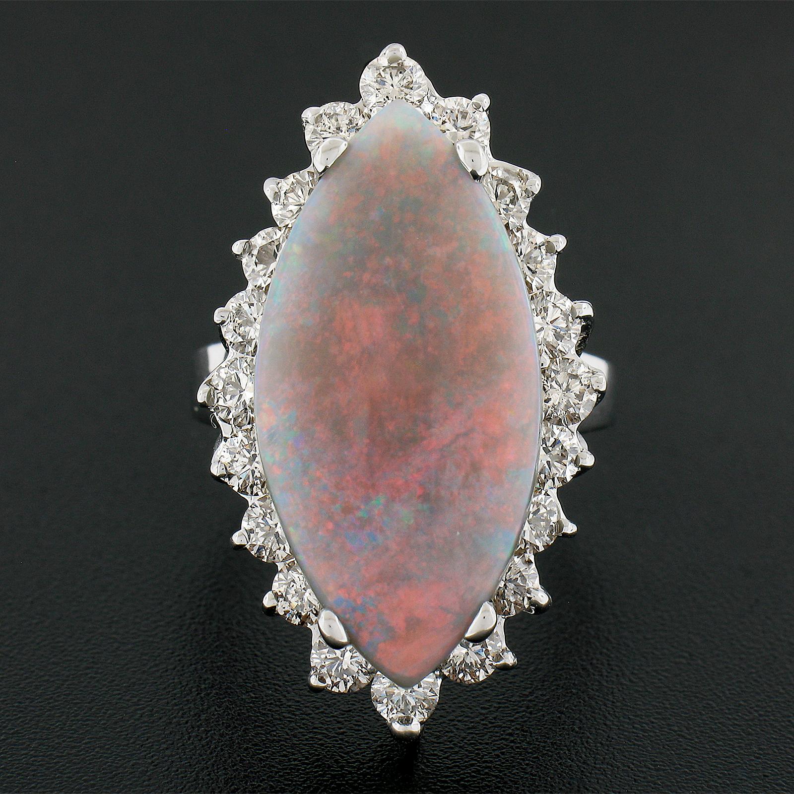 This stunning and uniquely shaped vintage cocktail ring features a large and absolutely breathtaking cabochon marquise opal stone that displays fiery and obvious orange and red play of colors over its natural gray and untreated color. The center
