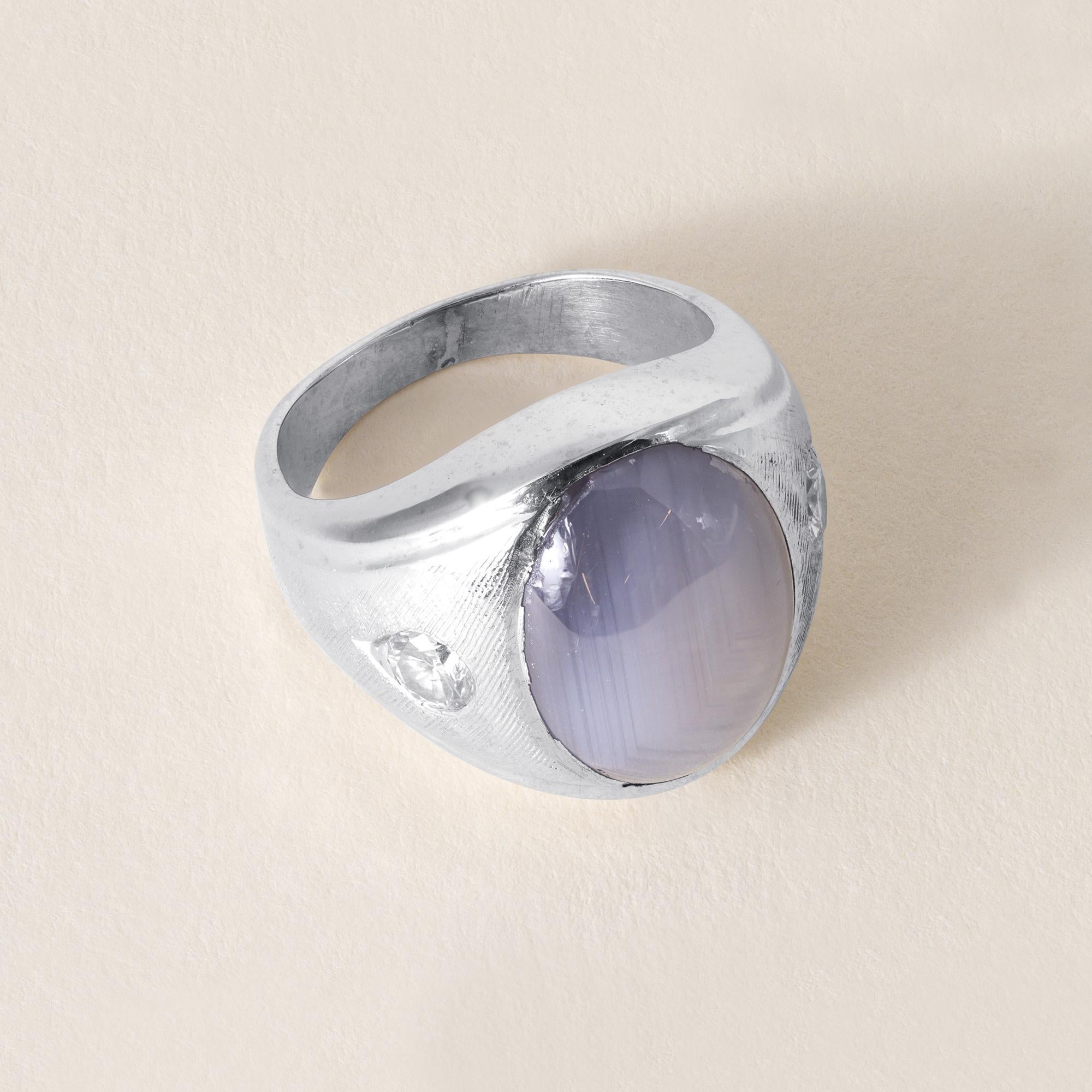 This is a vintage star sapphire ring
Circa 1960
Features:
13.50 carat lavender start sapphire, with a very nice prominent star phenomena
Bezel set in a Florentine etched white gold band
Two round brilliant diamond accents weigh 0.50 carats
F/G