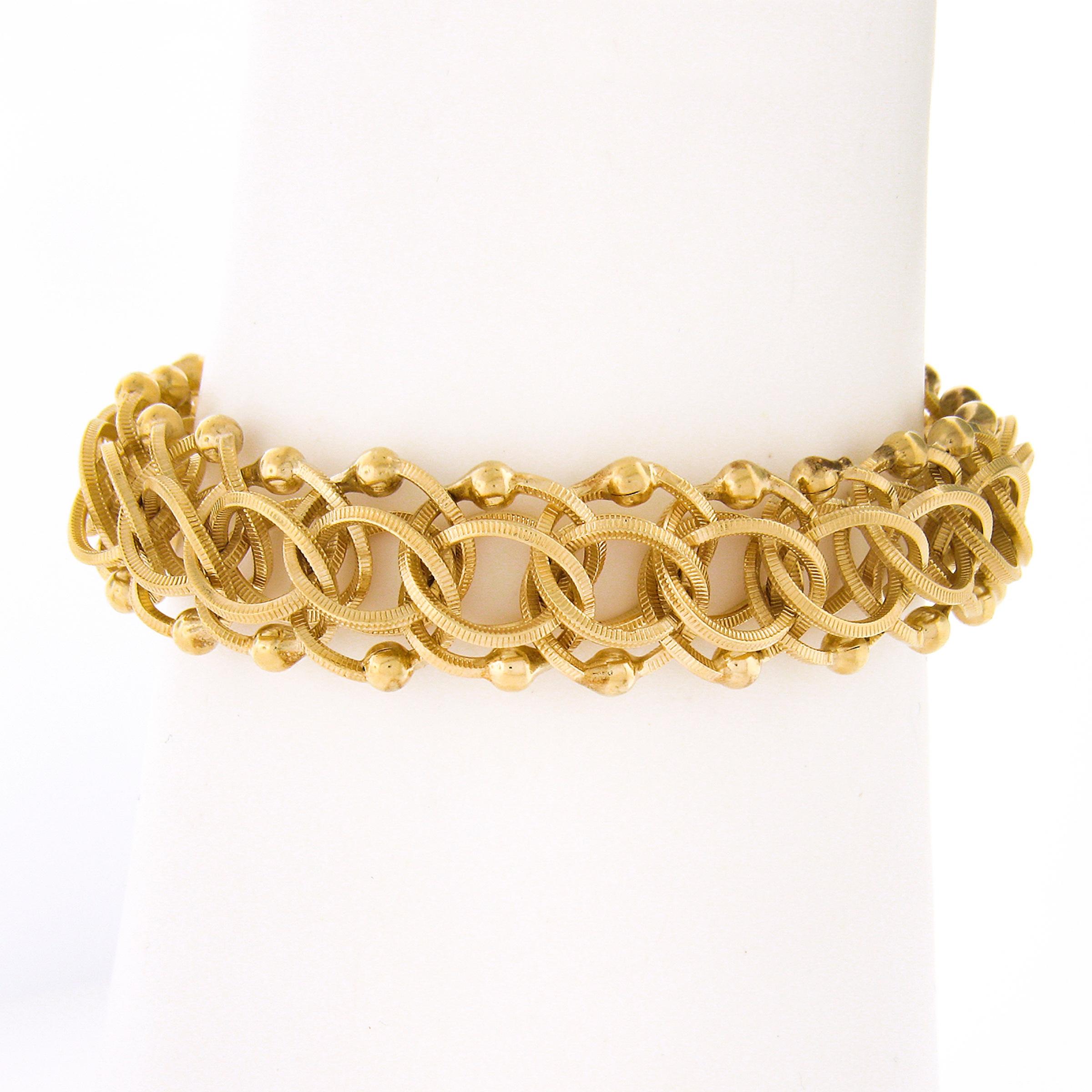 Here we have a gorgeous vintage charm bracelet that is very well crafted in solid 14k yellow gold, featuring a nicely textured double loop open ring link throughout. This fine bracelet lays smoothly on the wrist and looks absolutely bold worn alone