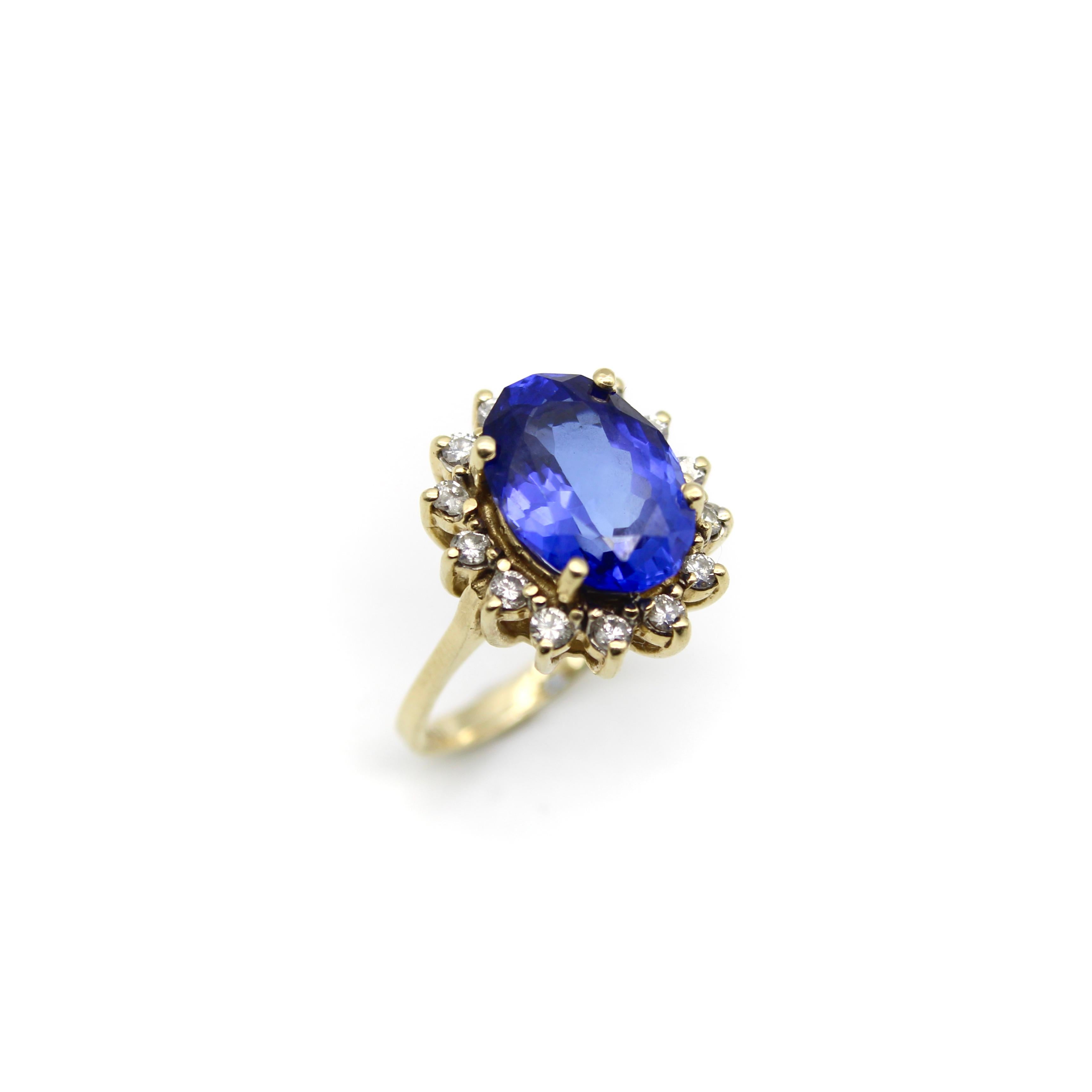 This beautiful vintage 14k gold ring features an oval tanzanite framed by a halo of round brilliant diamonds. The tanzanite is a gorgeous rich blue color with purple undertones, which is considered to be one of the most desirable shades of