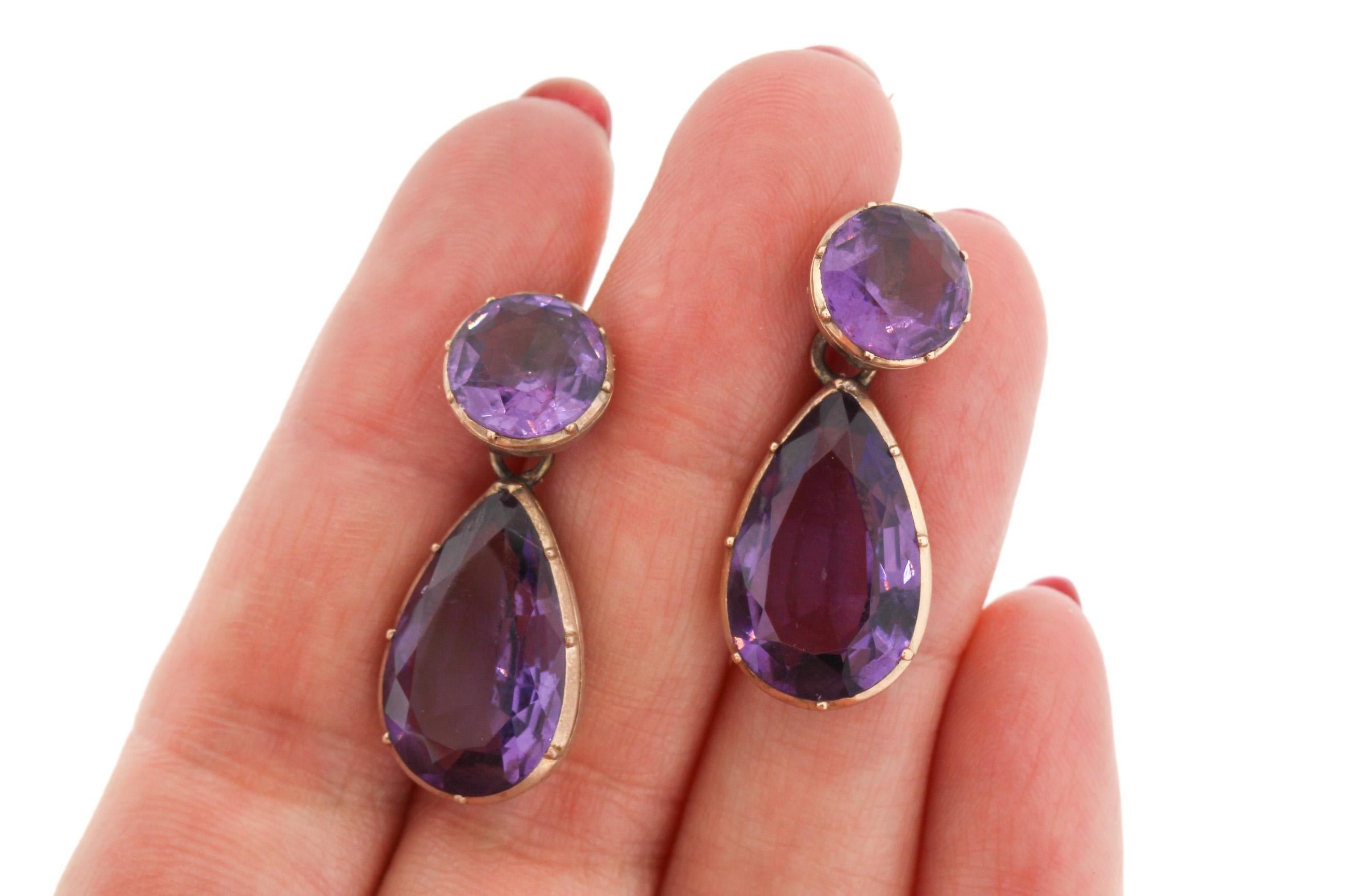 Vintage 14k Gelbgold collet set Amethyst Anhänger Ohrringe, um 1940. Die Teile könnten aus einer früheren Zeit stammen. Ein runder Amethyst in Spannzangenfassung hängt an einem birnenförmigen Amethysten. Die Ohrringe haben lange Schwanenhaken. Ein