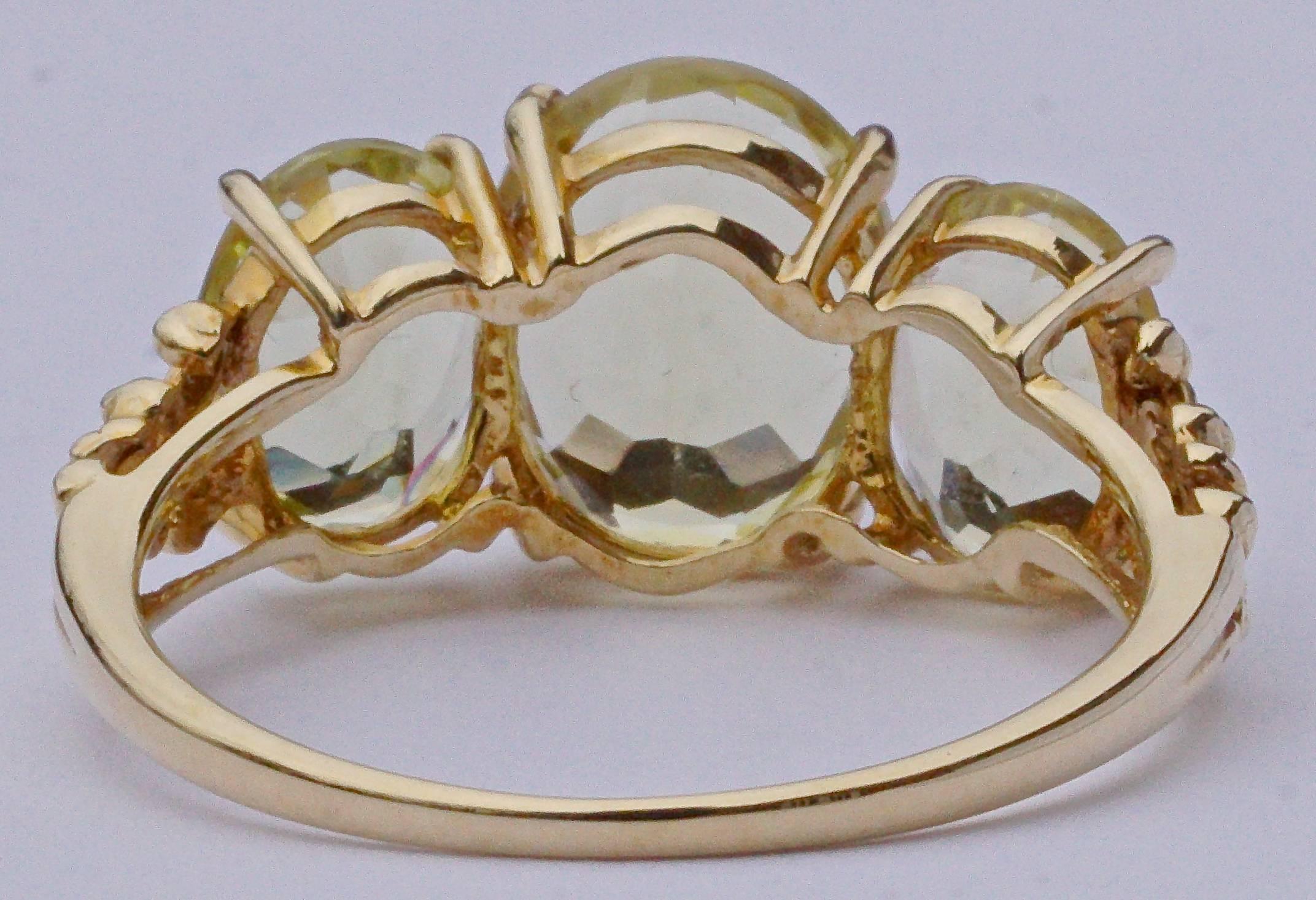 14K gold ring featuring three beautiful faceted enhanced citrines in a simple setting, and with a fancy scroll design to the shoulders. These gemstones have a lovely greenish tint. The largest stone measures length 1cm / .4 inch by width 8.5mm /.33