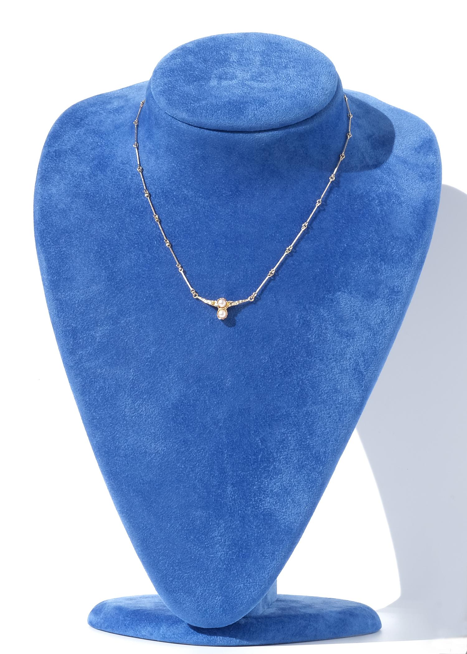 This vintage necklace, Cheek to Cheek, is crafted in 14 karat gold and features two vertically aligned cultured pearls. The pearls are set in a sculptural gold frame with an organic, textured surface. The pendant is integrated into a delicate bar