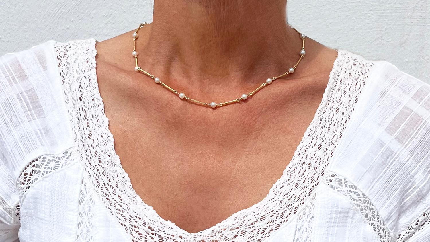 This 14 karat gold necklace is made of rectangular golden bars which are linked together. The gold links have a hammared surface and each link is embraced by cultured pearls. The necklace closes easily with a box clasp and a safety hook.

The