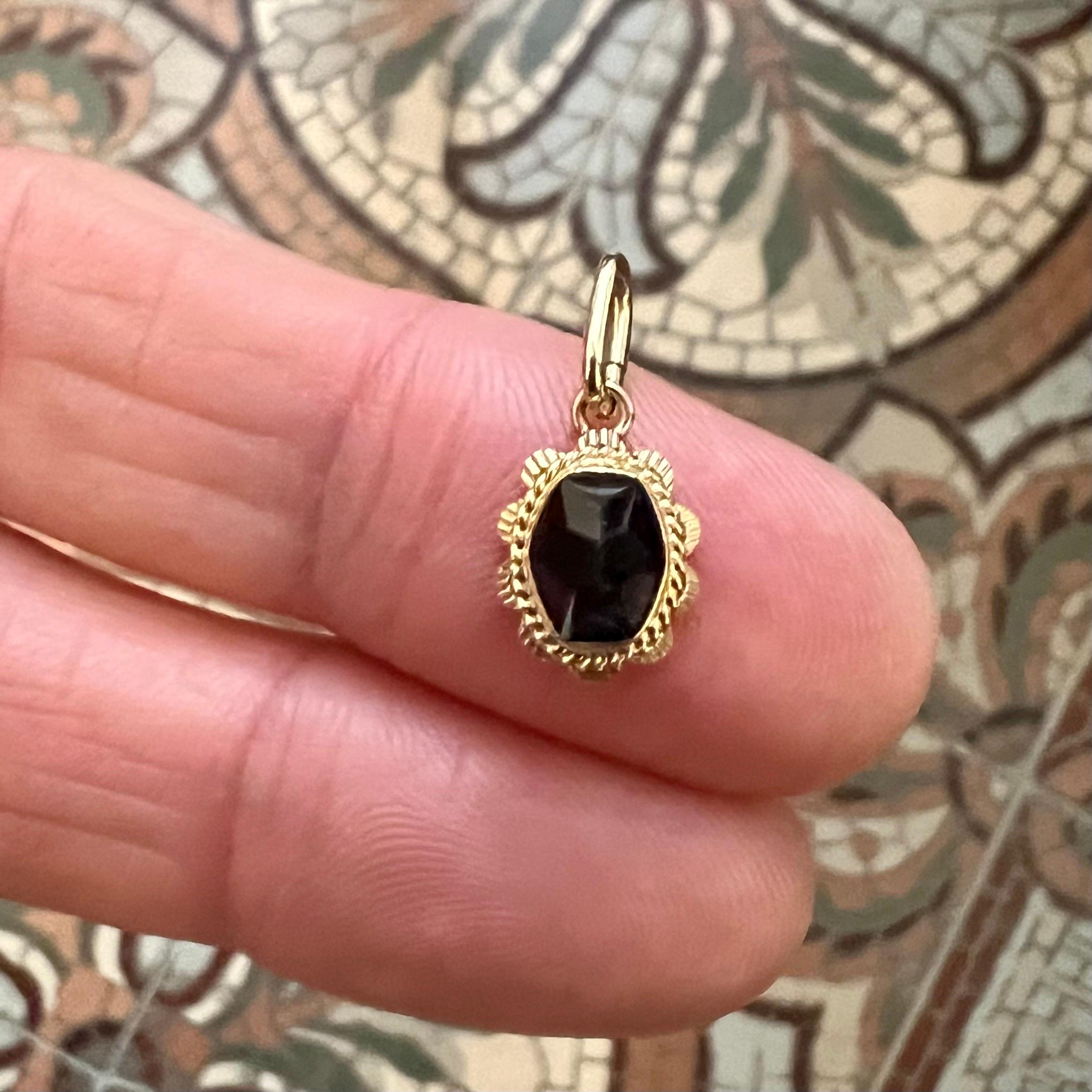 Questo affascinante ciondolo vintage è un bellissimo esempio di artigianato ed eleganza senza tempo. Realizzato in oro 14 carati, presenta al centro una splendida gemma di granato taglio rosa, circondata da dettagli intricati che ne esaltano il