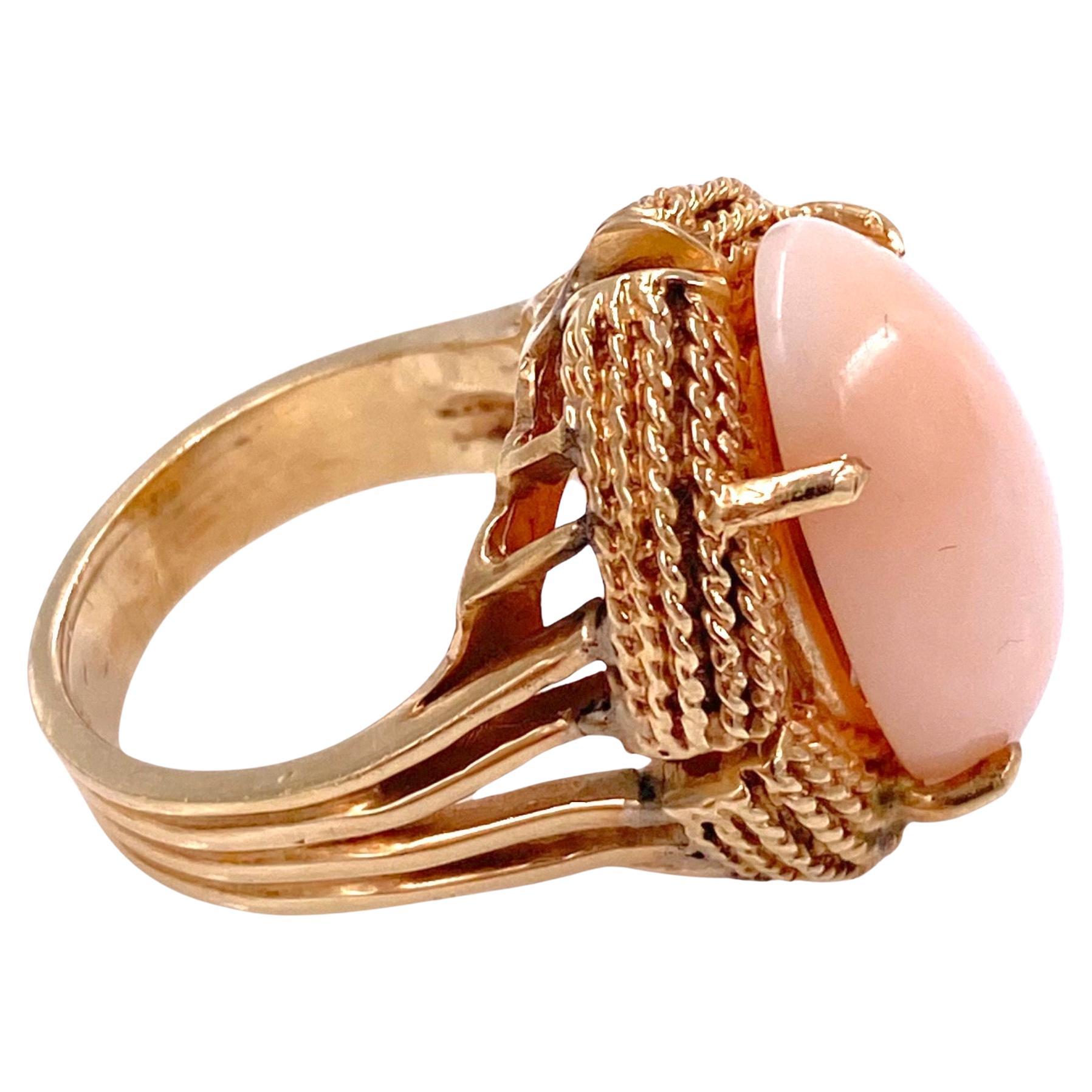 Crafted in 14K yellow gold, the ring features a large oval angel skin coral cabochon set within a ripe style gold bezel, supported by split shoulders, complete by a five millimeter wide band.
Coral: 21.5 mm L x 12.5 mm W x 6 mm