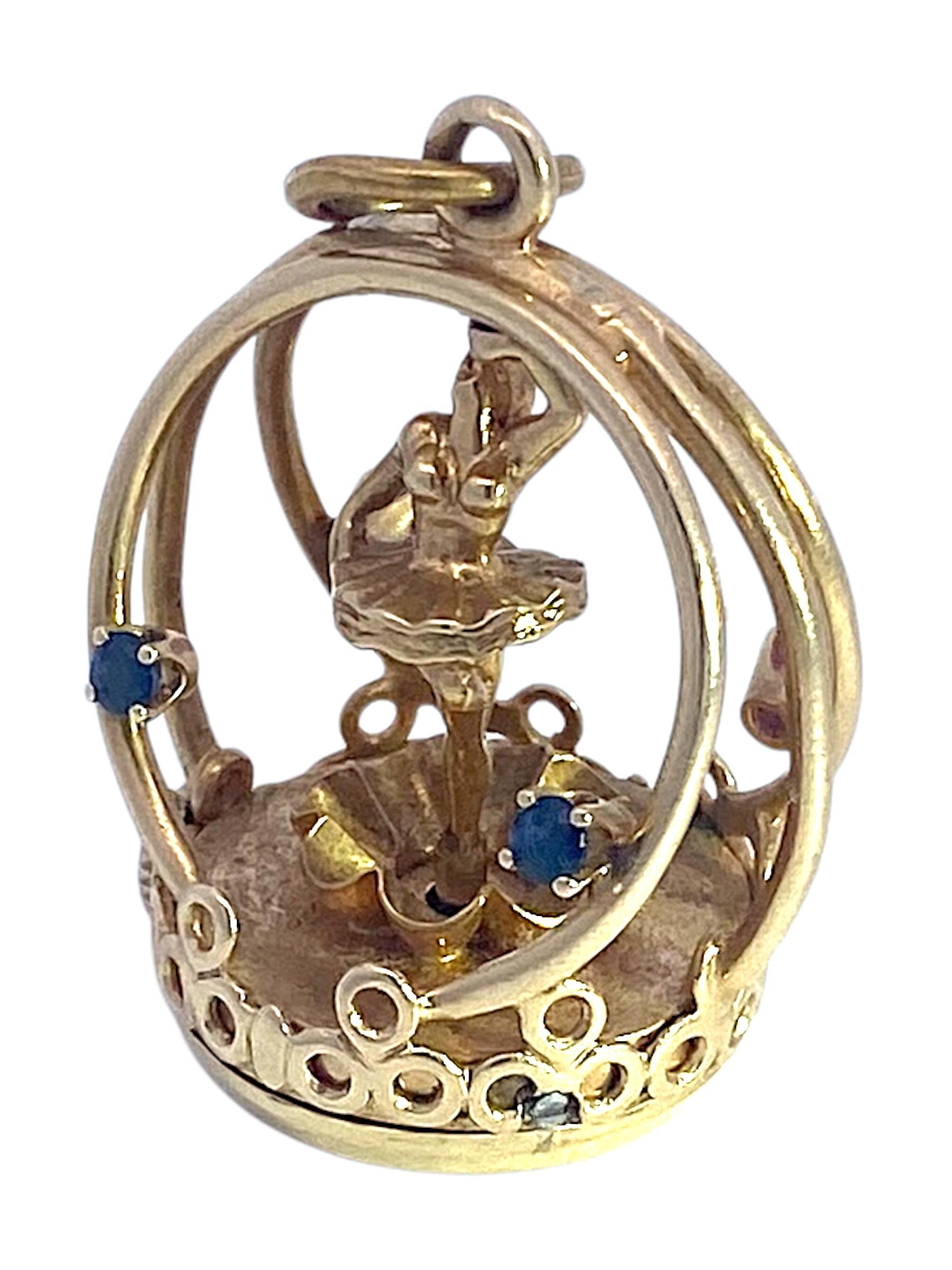 Crafted in 14K yellow gold, this vintage articulating living charm features a pirouetting ballerina design encased within a circular frame. The piece is adorned with round-cut rubies and blue sapphires, adding vibrant red and blue accents. The