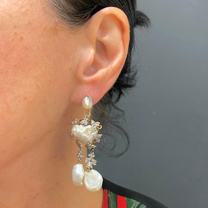 Un par de pendientes barrocos vintage de oro de 14k con perlas y diamantes.
En la parte superior de cada pendiente se escenificaba una perla luminosa de forma orgánica. A continuación se suspende
la pieza central de una perla barroca más grande,