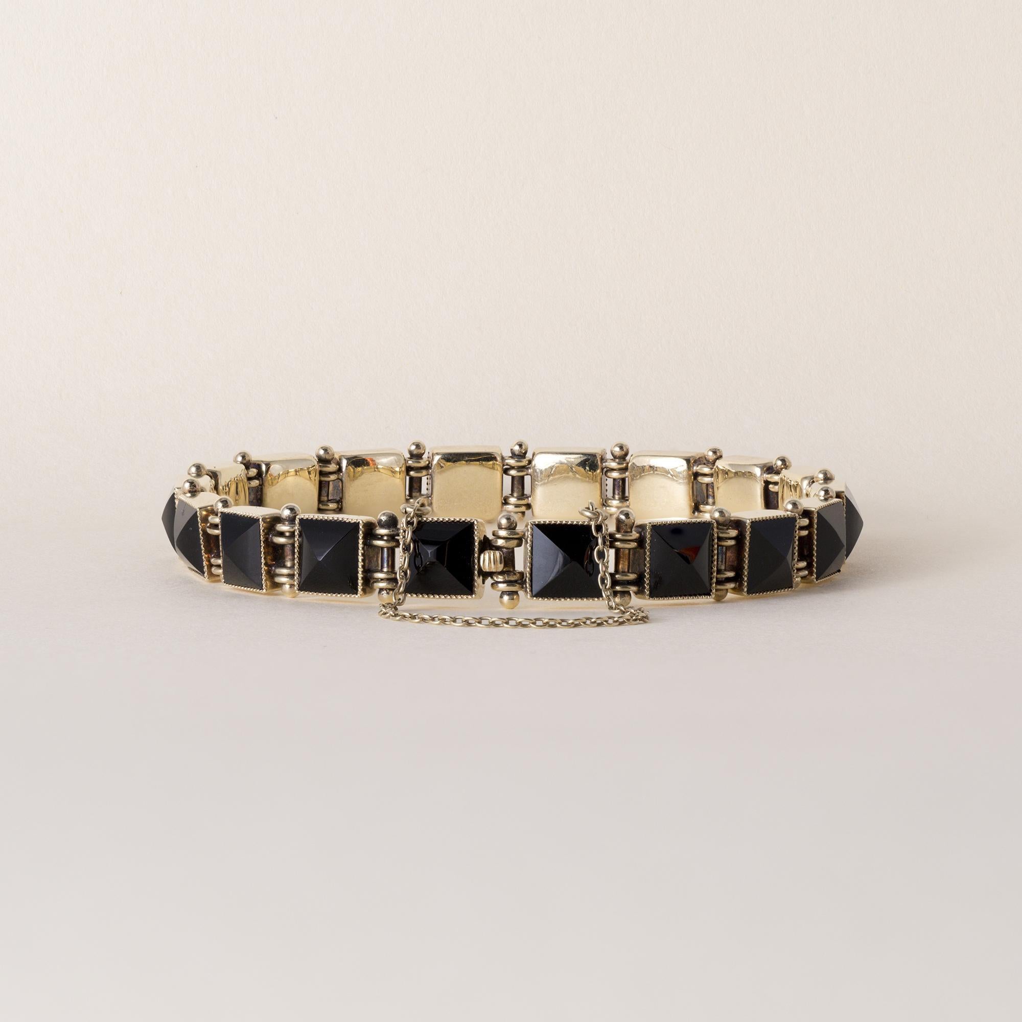Vintage Gold Schwarzer Onyx Pyramidenarmband
CIRCA 1950
Einzelheiten:
18 schwarze Onyx-Pyramiden-Edelsteine in quadratischen 14-Karat-Rahmen eingefasst
jedes Stück ist einzeln in einen quadratischen Rahmen aus 14-karätigem Gold gefasst, der mit