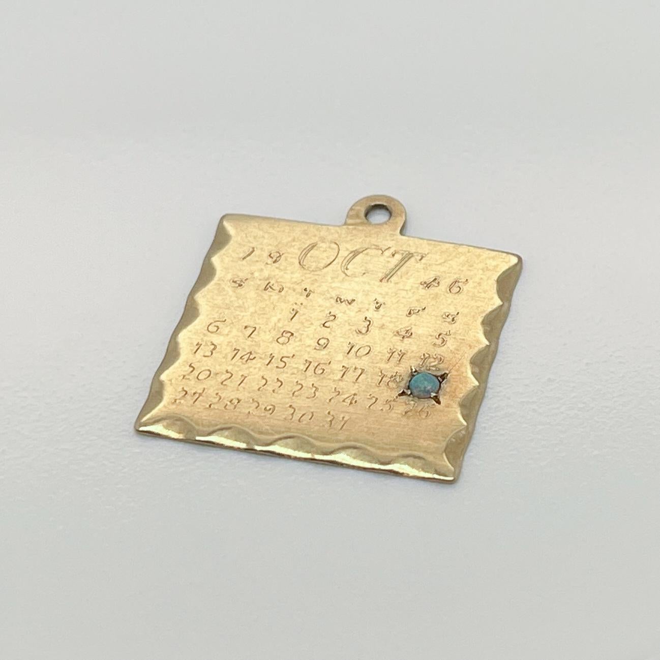 A vintage 14 karat gold charm for a charm bracelet. 

In the form of a calendar with the month of October inscribed on it from the year 1946.  

There is an opal inset on October 19th to mark a birth date of the birthday.  

The reverse is