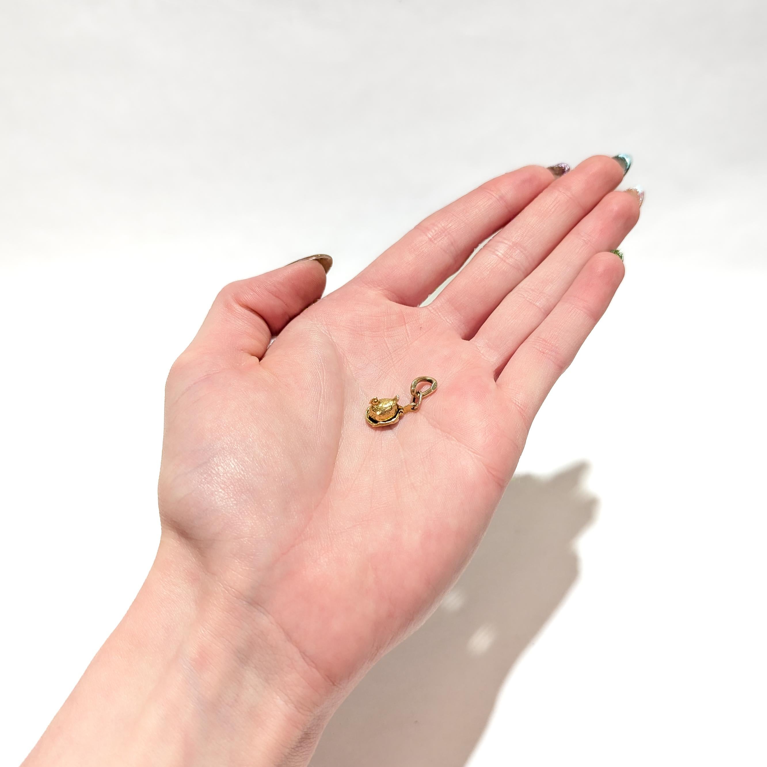 A fine vintage gold charm for a charm bracelet.

In 14 karat yellow gold.

In the form of a hen sitting on a nest. The hen's back is hinged and lifts up to reveal two chicks in the nest.

With an integral bail and and 2 jump rings to the hen's