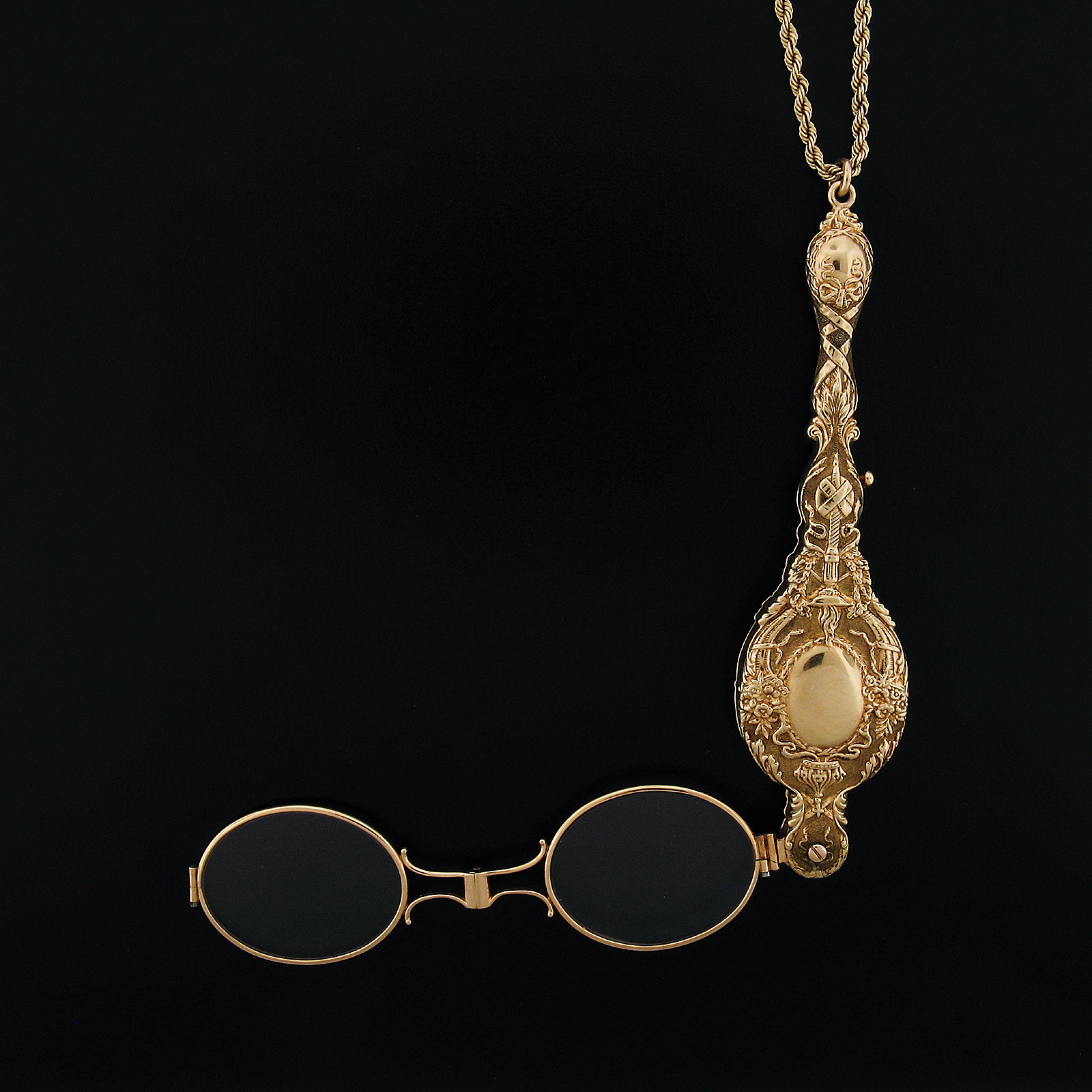 This vintage collectible lorgnette necklace is crafted in solid 14k yellow gold. It is very well detailed and features floral patterns throughout with an olympic style torch on both sides of the design. The lorgnette slides on a long, 35 inches rope