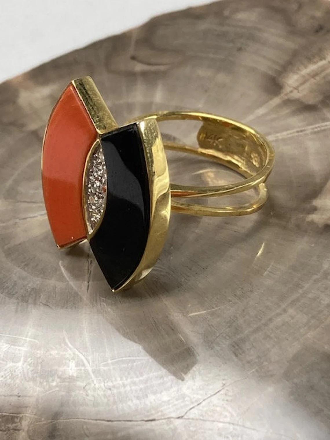 Vintage 14k Gold Coral & Onyx Ring with Diamond Accent, One-of-a-kind

This vintage ring truly is the perfect statement piece, with its unique coral and onyx beams, cocooning a cluster of dazzling white diamonds. It was made in the 1980s and