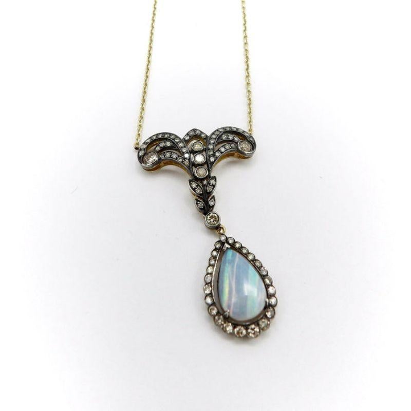 This is a remarkable vintage piece made in the style of antique Victorian jewelry, featuring a mystical opal gemstone. The necklace with pendant is composed of two parts; a top lace-like diamond studded organic motif connecting to a lower dangling