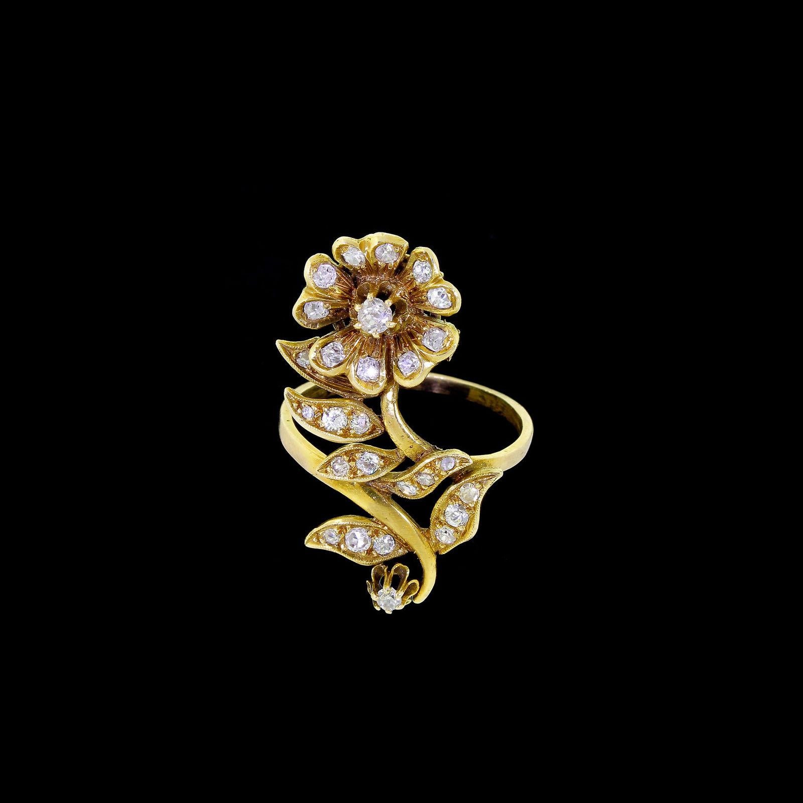 Dieser Ring ist wirklich beeindruckend: 27 Diamanten glitzern und funkeln in diesem langgestreckten floralen Design.
Der Ring ist europäischer Herkunft, er hat eine Mischung aus Diamanten im Minen- und Rosenschliff und ein paar, die wie