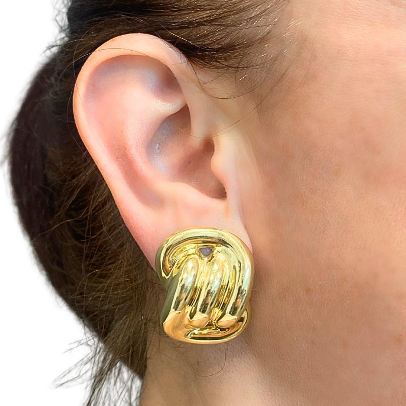 A pair of vintage 14k gold earrings in a swirl design.  High-polished finish makes them smooth and rounded, and generous volume gives them presence. Designed with an abstract swirl motif, these vintage earrings curve and fold like a soft ribbon.