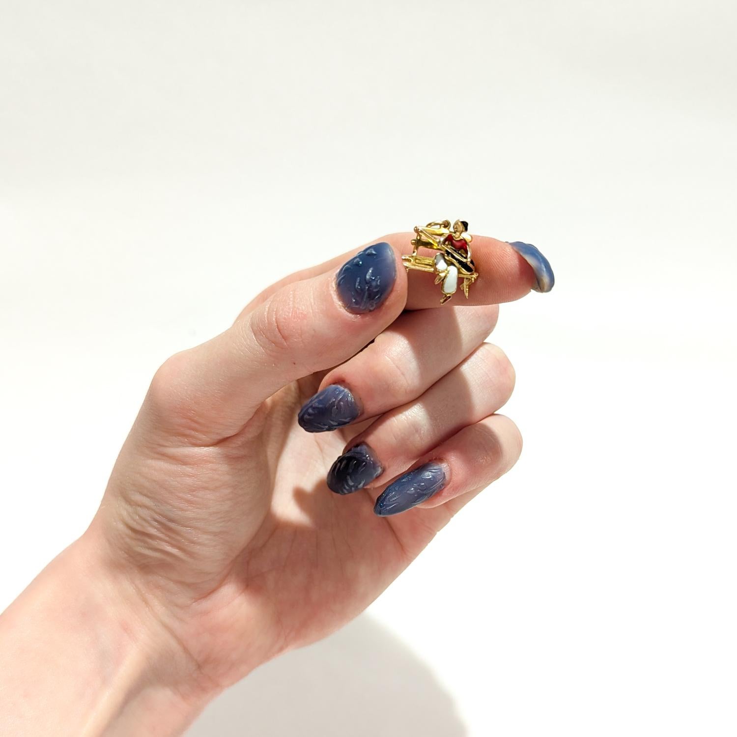Un bel ciondolo figurato d'epoca in oro e smalto.

In oro giallo 14 carati.

A forma di chitarrista seduto su una panchina con smalto che evidenzia i vestiti, la chitarra e i capelli/capelli.

Con un anello di chiusura integrale e un anello di