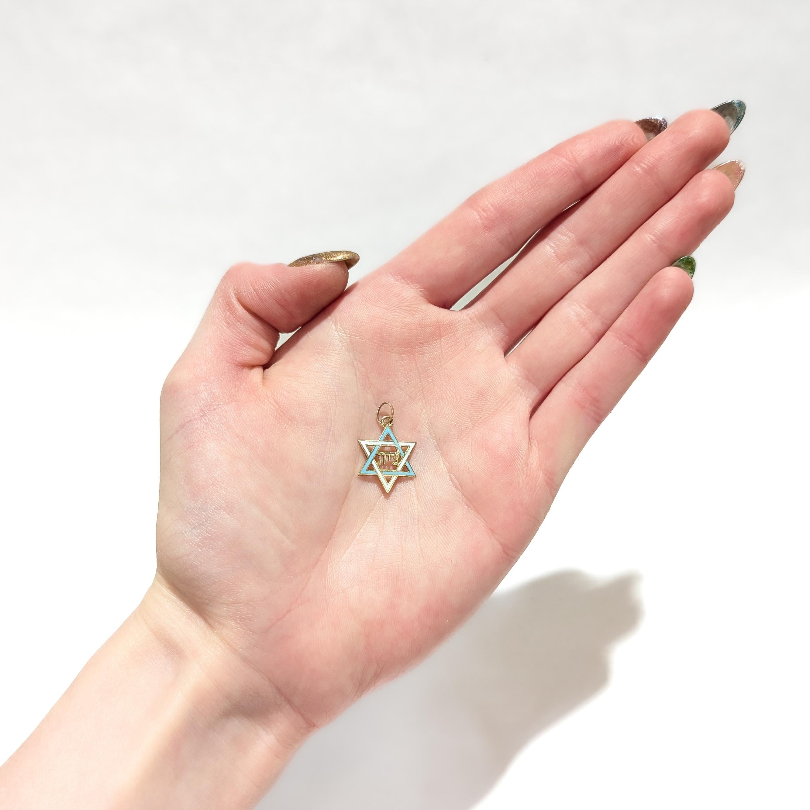 A fine vintage gold & enamel figural charm.

In 14 karat yellow gold.

In the form of the Star of David with blue and white enamel decoration. 

The center of the charm decorated with the Hebrew for 'Zion' (צִיּוֹן).

With an integral bail & jump