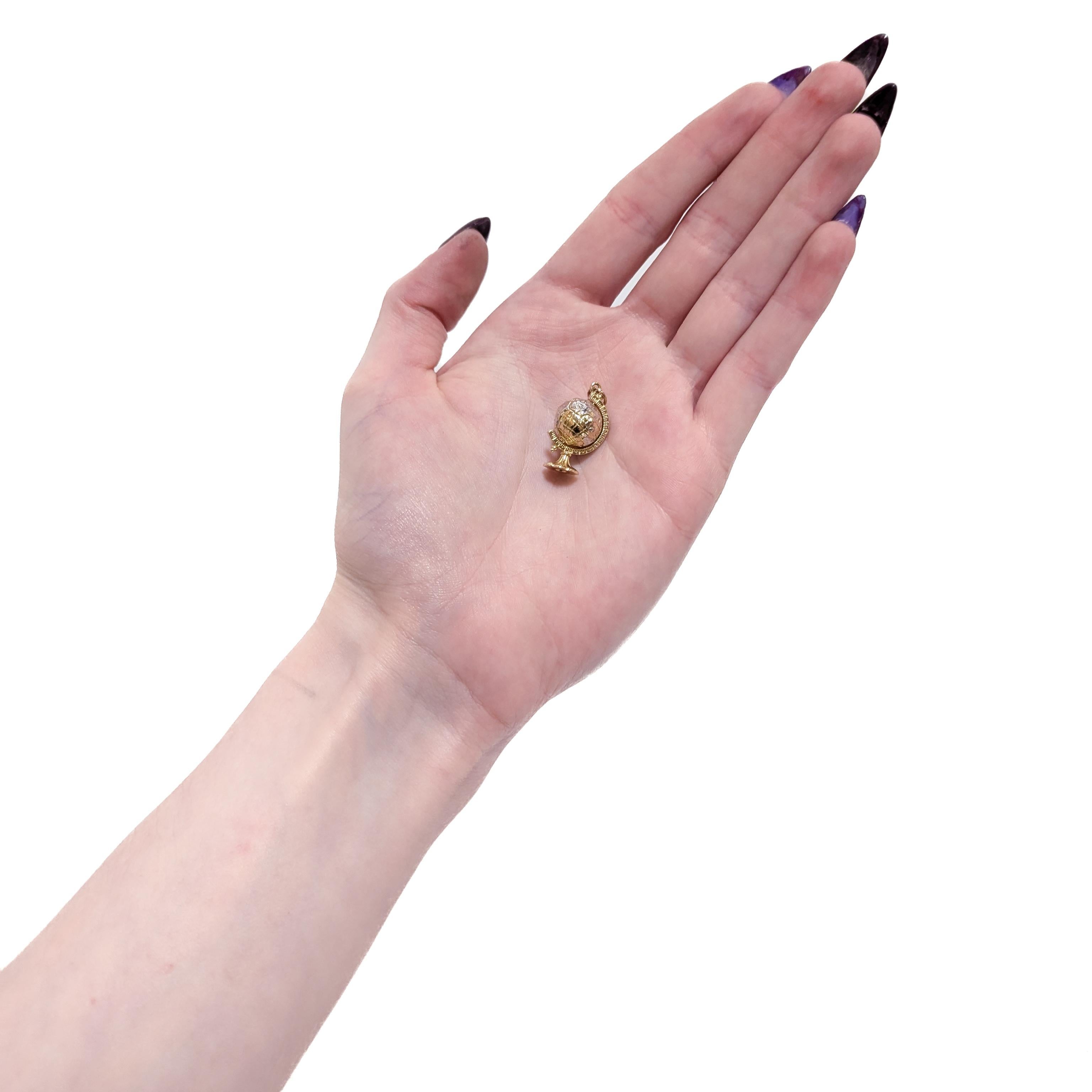 Une breloque figurative vintage en or.

En or blanc et jaune 14 carats.

Sous la forme d'un globe sur un support, avec une inclinaison standard de 23,5° par rapport à la verticale. Le globe tourne librement.

Les détails et les continents sont
