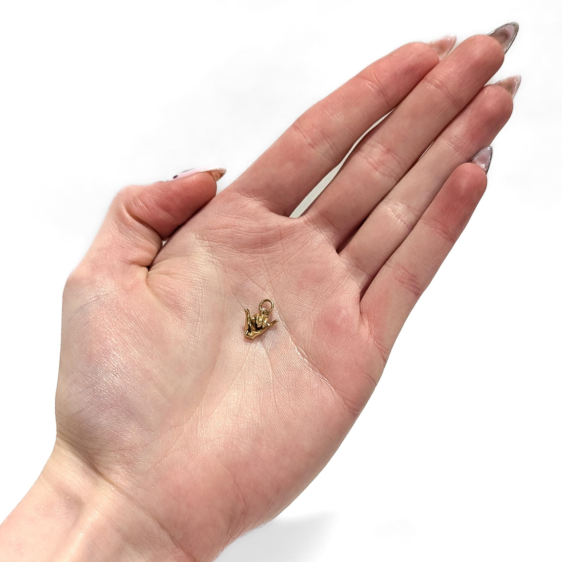 A fine Mid-Century charm for a bracelet.

In 14 karat yellow gold.

In the form of a shaka ('hang loose') hand sign from Hawaiian culture (or possibly a telephone hand gesture).

Simply a wonderful hand charm for a bracelet!

(Chain for display