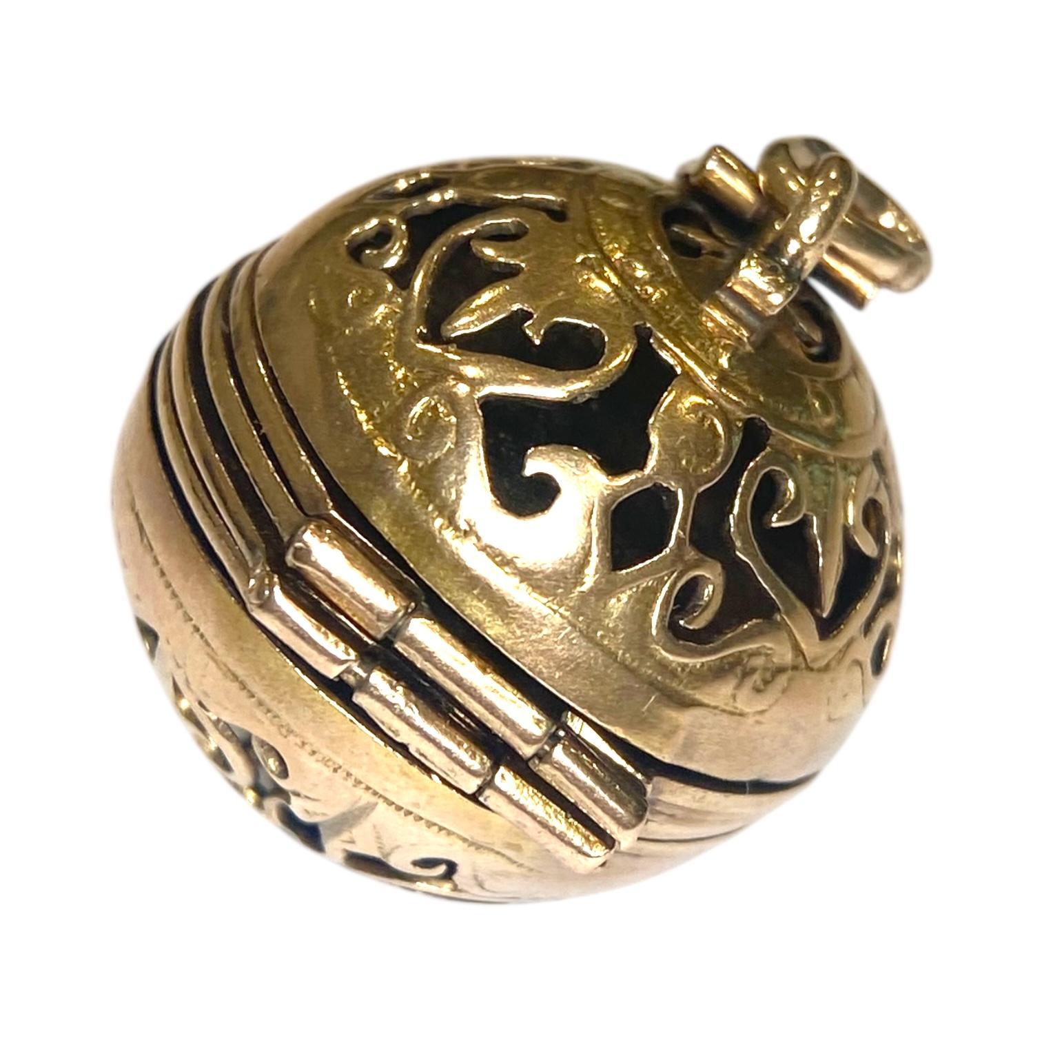 Vintage 14K yellow gold pendant designed as a pierced dimensional sphere, depicting a scrolling heart motif throughout. The locket features a hinged curved arm that release to reveal folded accordion style links with three photo