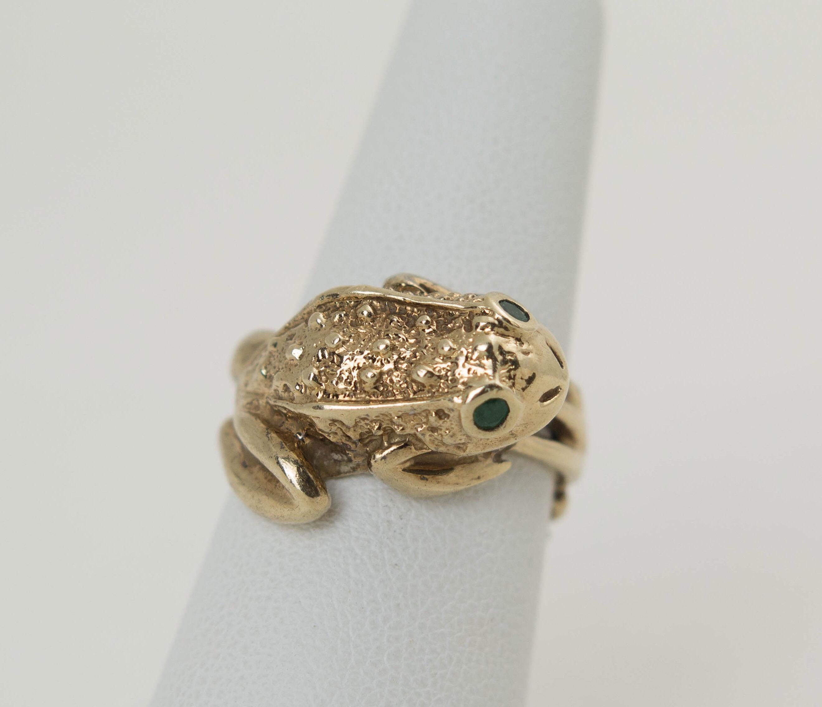 A whimsical vintage 14K gold ring in a form of a frog. The frog has a pair of emerald eyes and textured gold body. its elongated legs wrap around as the ring shank, 
Marked 14K and maker's mark. Just a wonderful ring!
Ring size: 6.5. Weight: 8.8
