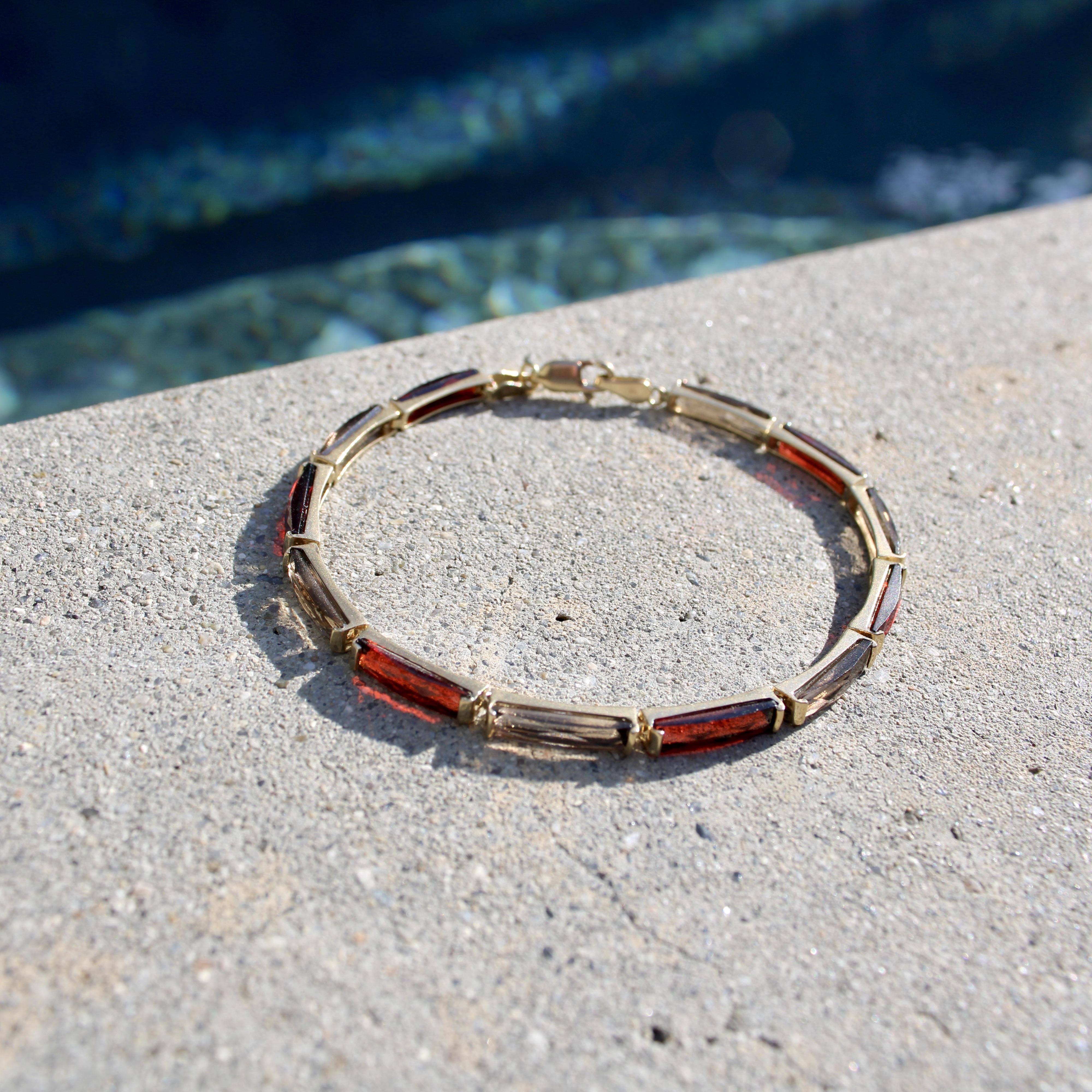 Ce bracelet vintage en or 14k présente une alternance de grenats et de pierres de quartz fumé en taille française allongée. Les pierres s'insèrent parfaitement dans des montures à demi-béliers, de sorte que chaque pierre constitue un maillon, et que