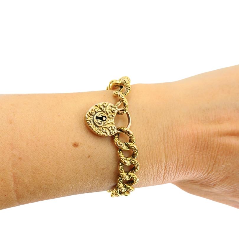 Ce magnifique bracelet en or 14k est orné d'une gravure sur les maillons et d'un fermoir cadenas en forme de cœur. Pesant environ 12 grammes, la pièce dégage une élégance intemporelle grâce à ses volutes complexes. Le cadenas en forme de cœur sert à