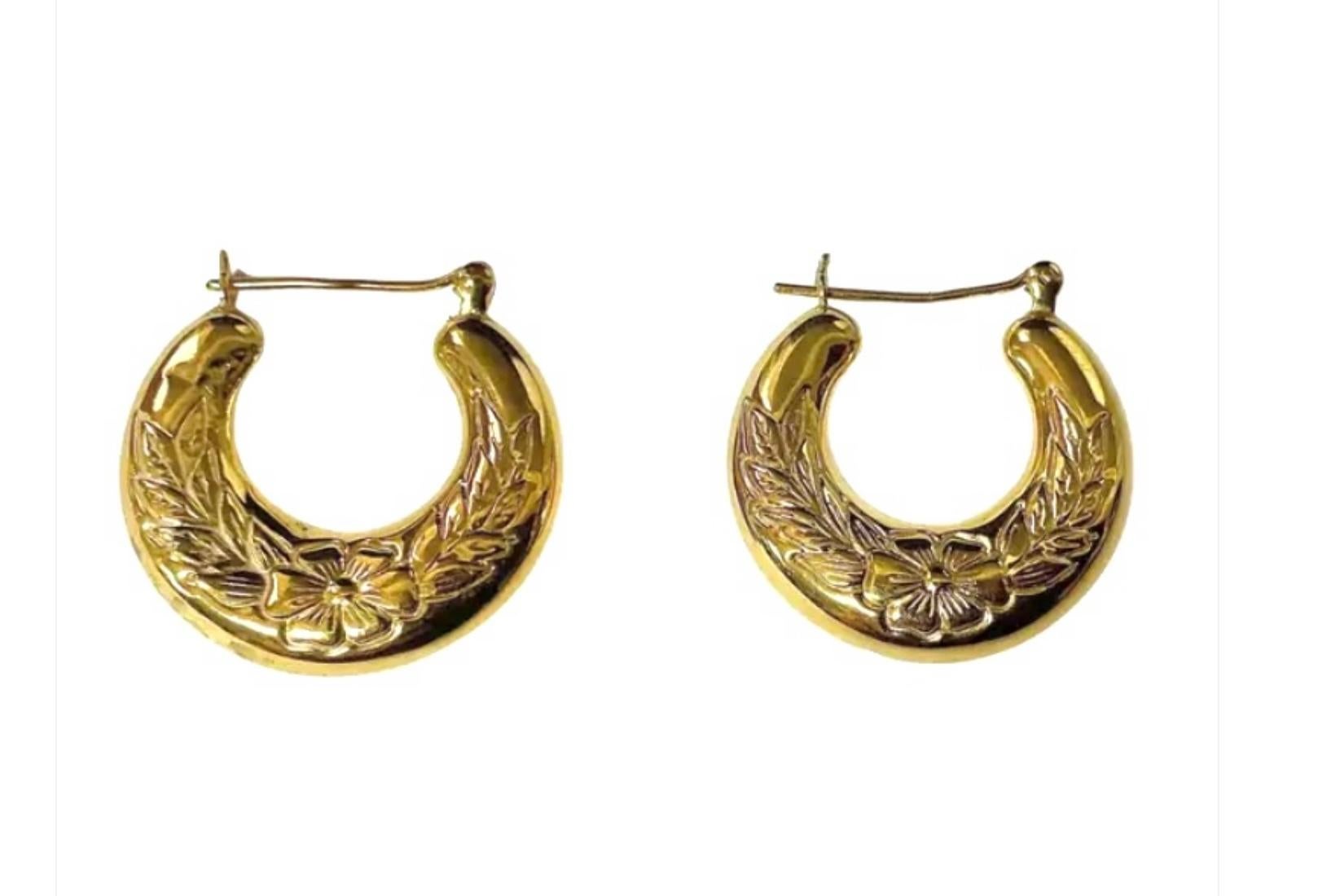 14K Gold Hoop Earrings featuring a softly rounded crescent shape with a raised floral and leaf motif for added texture and shine. Each earring is fitted with a hinged post and secure latch-back closure for comfortable wear. Measures approximately