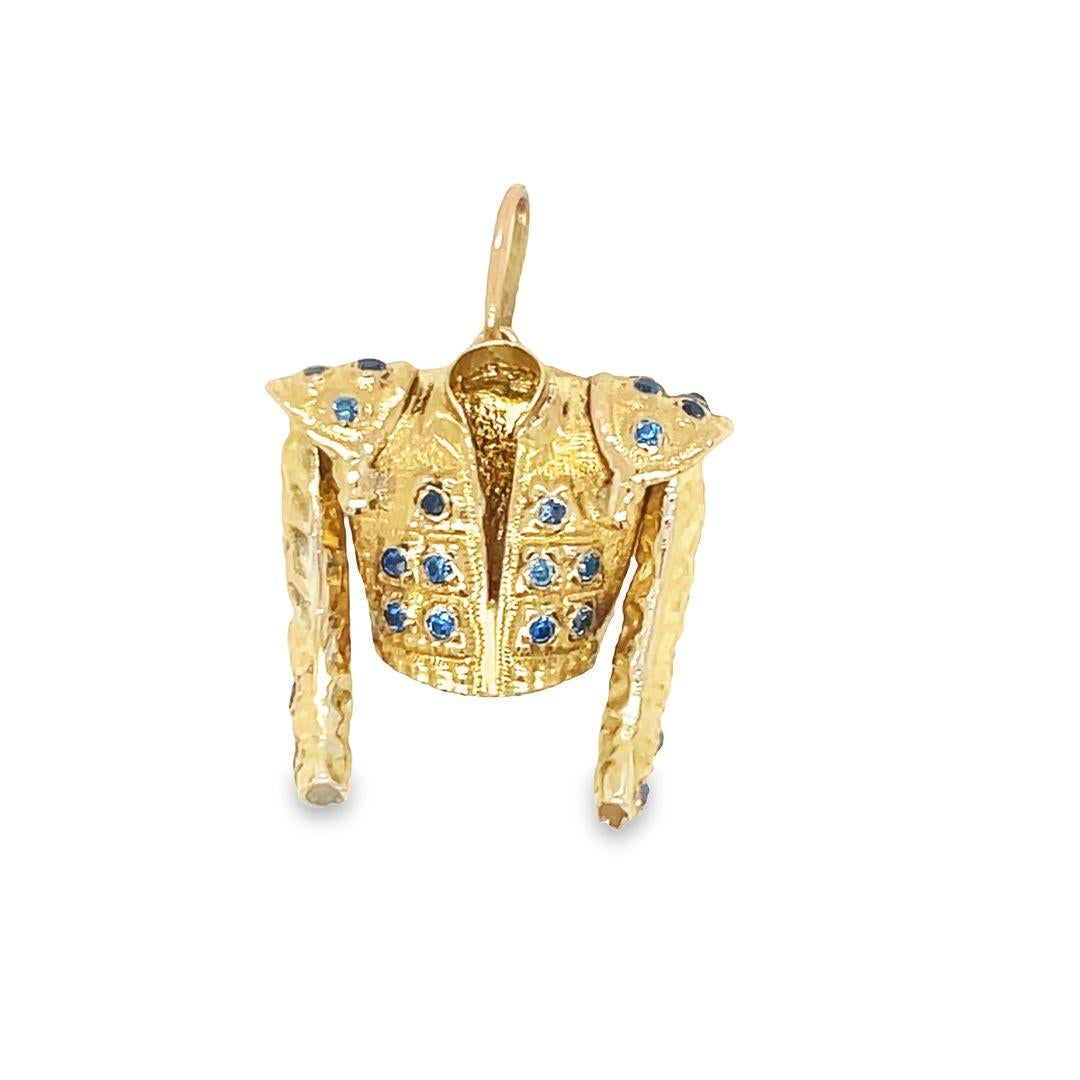 A stunning Matador's Jacket in 14K yellow gold charm, meticulously crafted with superb detail. This charm showcases 3-dimensional design of a matador's jacket, adorned with twenty-nine (29) enhanced Blue Sapphires, adding a touch of elegance.