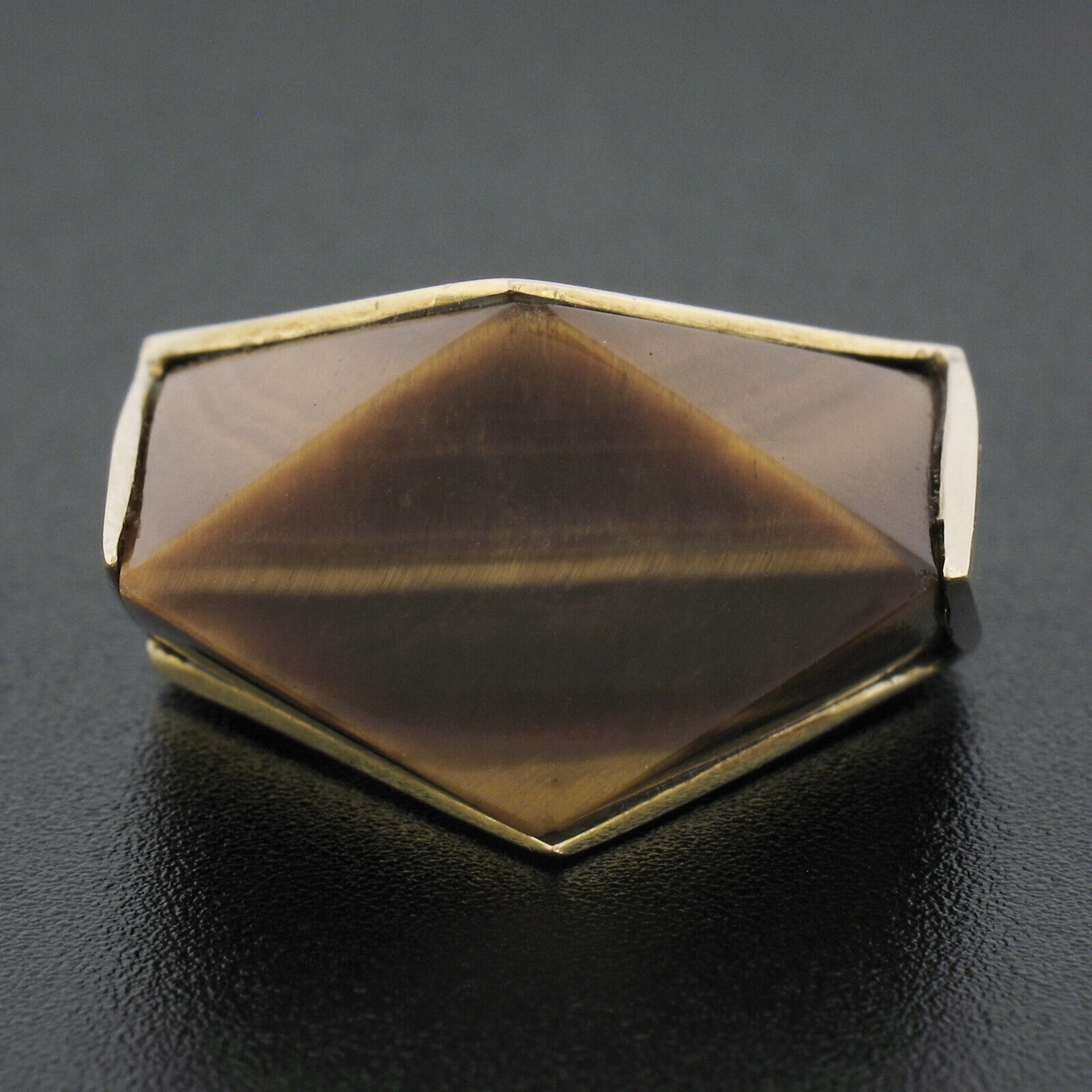 This solid and well made vintage statement ring was crafted in the 1960's from solid 14k yellow gold and features a wonderful, large, tigers eye stone with a unique geometric custom cut. This beautiful polished stone displays silky looking
